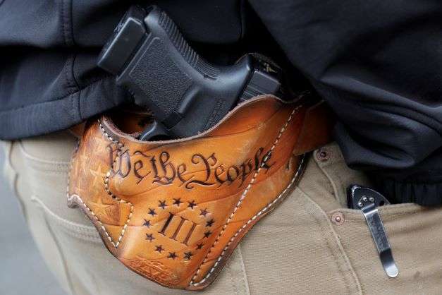 An attendee at a gun rights rally open-carries his gun in a holster that reads "We the People," from the Preamble to the United States Constitution on Jan. 18, 2019, at the Capitol in Olympia, Wash. Advocates say permitless carry makes people safer. Opponents say it makes it more dangerous for ordinary people, and for police officers. (AP Photo/Ted S. Warren, File)