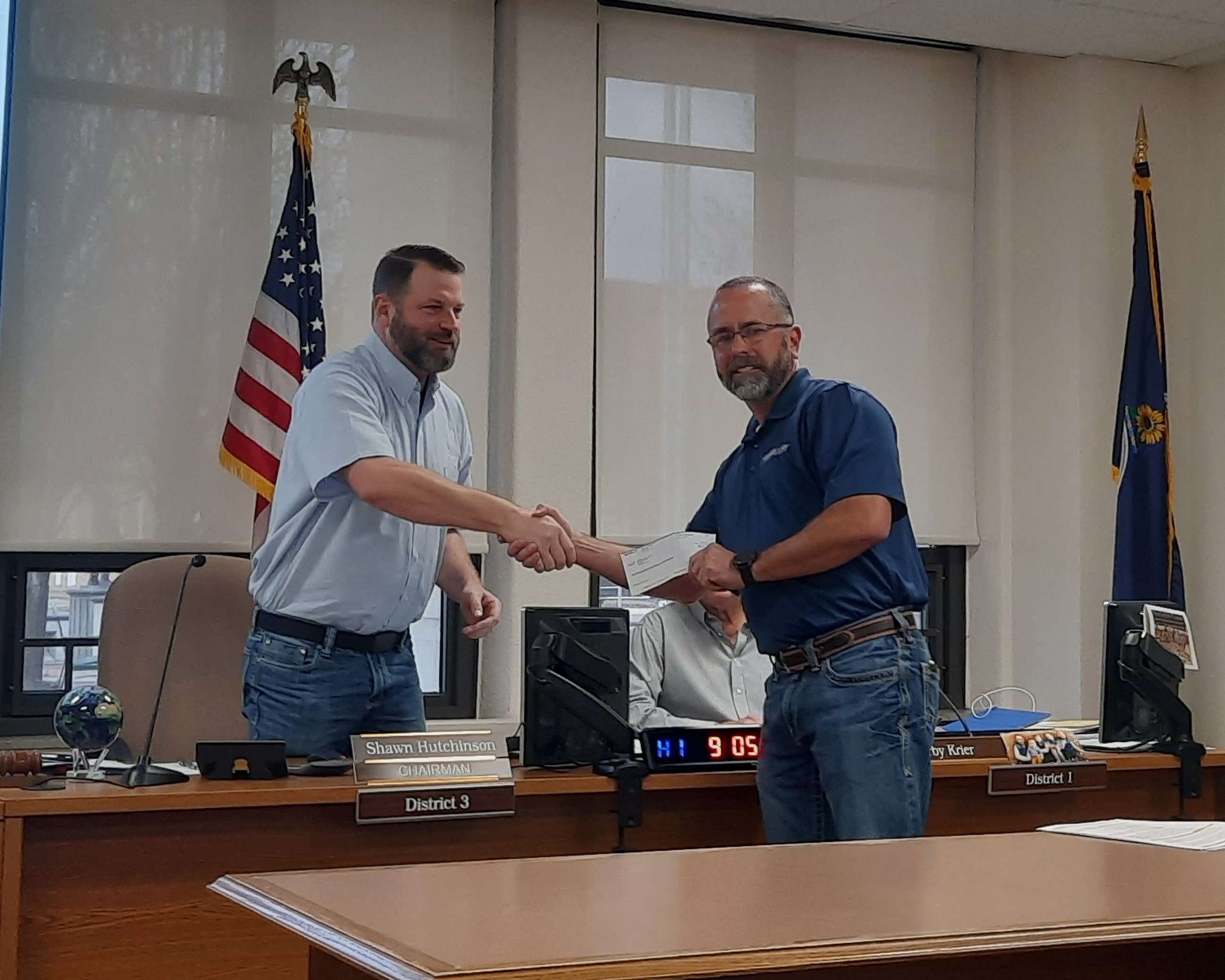 Justin Phillips with Magellan Midstream Partners, LP hands Barton County Commission Chair Shawn Hutchinson a check during Wednesday's meeting. The donation will be used to purchase an Automated External Defibrillator for the Barton County Sheriff's Office.