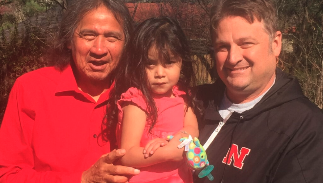 Frank LaMere, at left, and John Maisch hold a young girl, Arianna Boesem, who was born on the Pine Ridge Indian Reservation with fetal alcohol syndrome. LaMere, who first raised concerns about Whiteclay beer sales, died in 2019. (Dennis Carlson courtesy of the Nebraska Examiner)