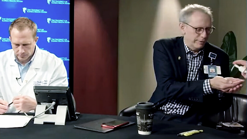 Steve Stites and Dana Hawkinson prepare for the first video briefing about COVID-19 after the arrival of the first patient two years ago. (Kansas Reflector screen capture from University of Kansas Health System video)