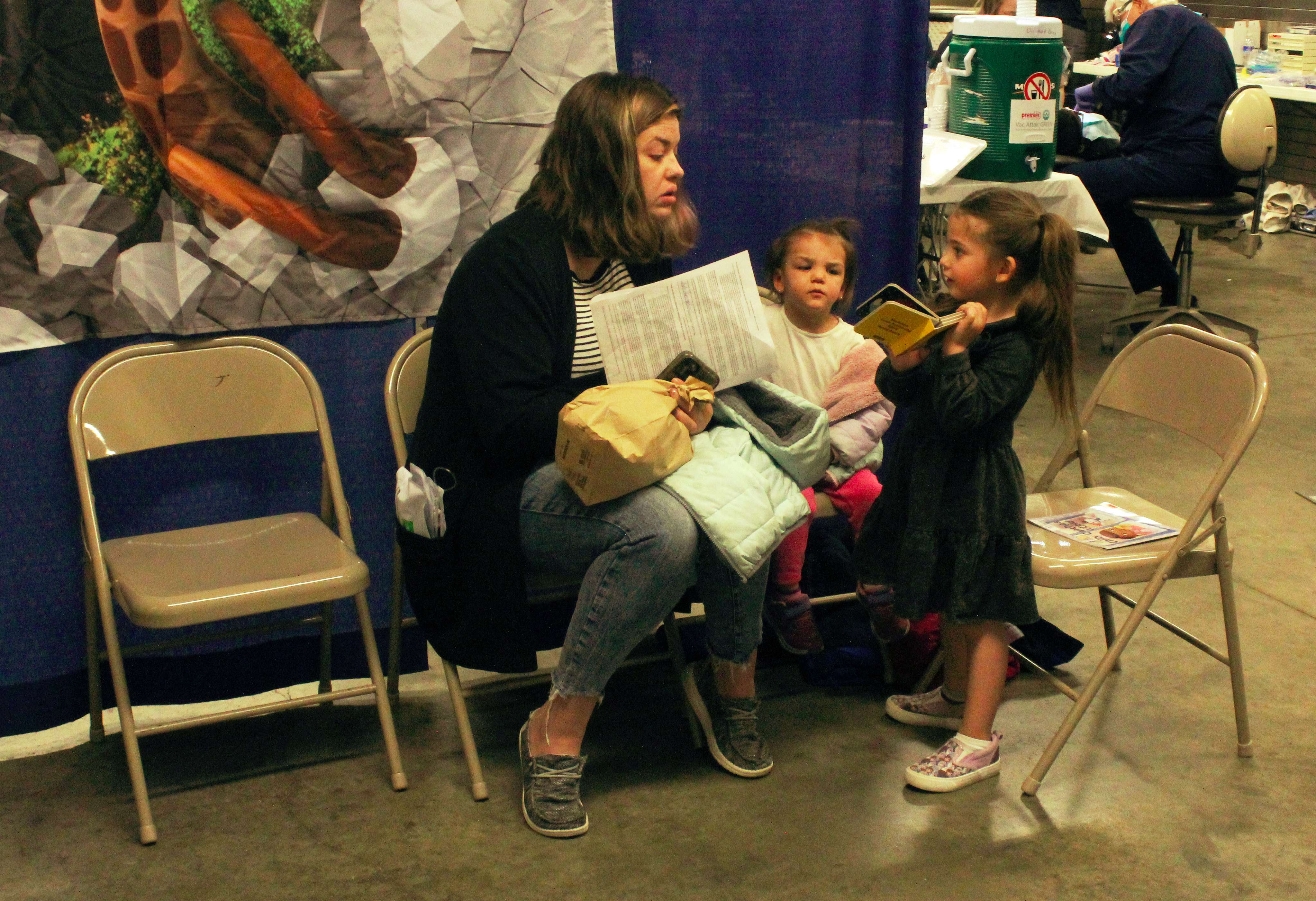 Taylor Springfield of Ellis with her daughters Eberly and Kinly, both 3, read books while they wait for the girls to receive free dental cleanings at the Kansas Mission of Mercy on Friday in Hays. Photo by Cristina Janney / Hays Post