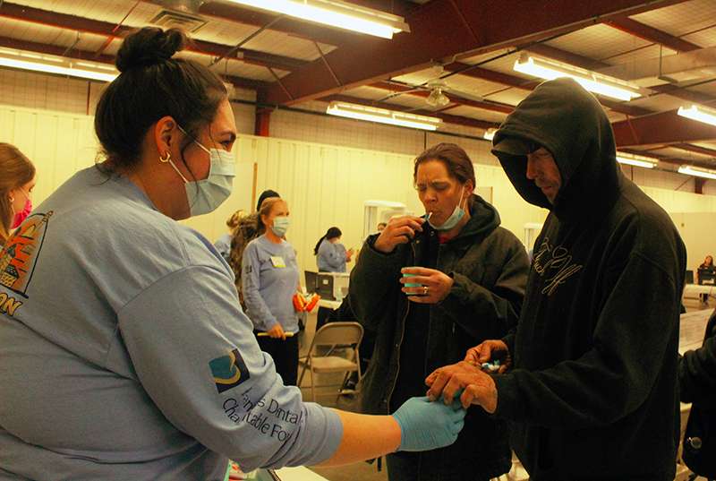 A volunteer helps dental patients get their teeth brushed before treatment Friday. Photo by Cristina Janney / Hays Post