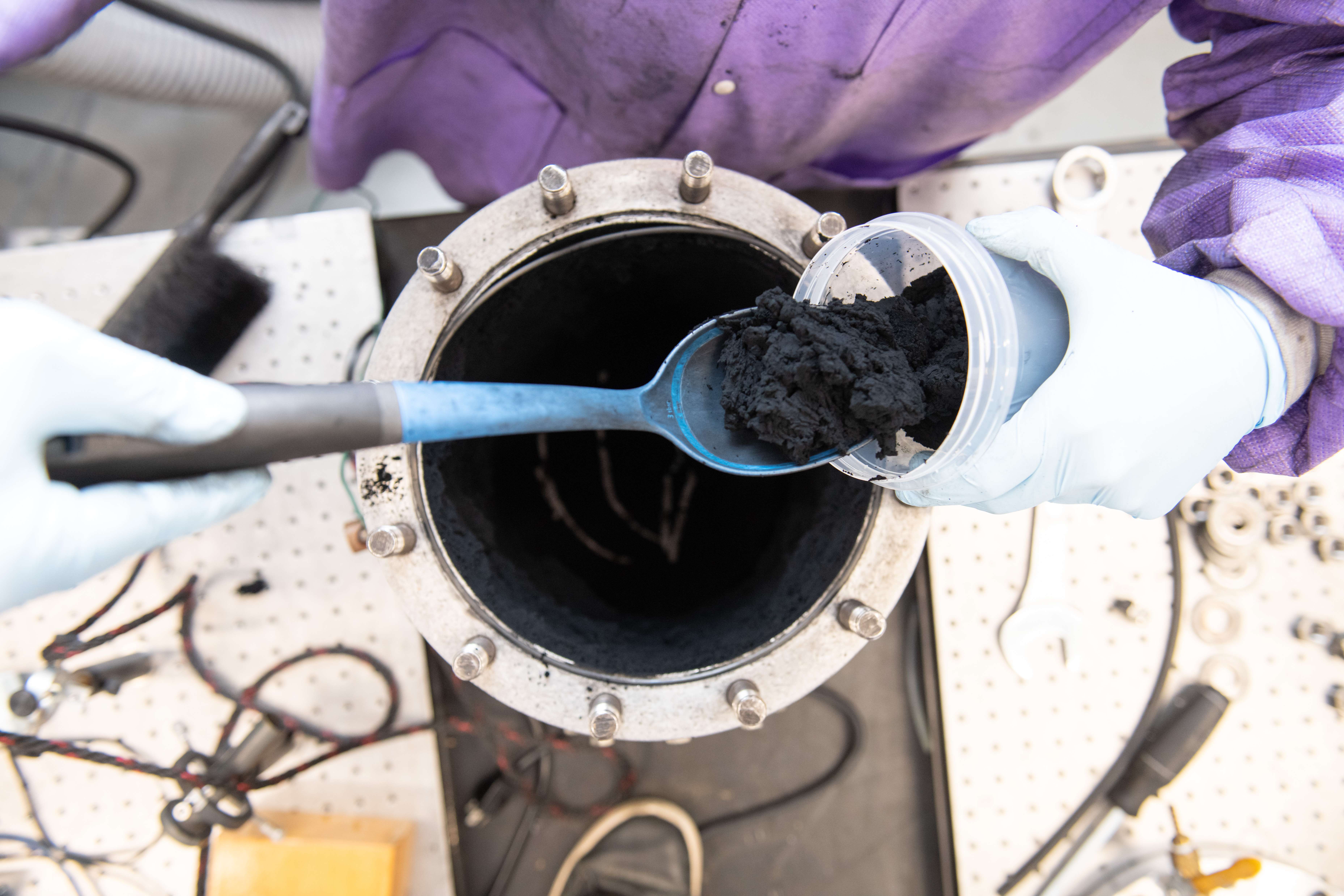 A Kansas State University researcher scoops out large quantities of graphene from a small detonation chamber. A K-State-patented method of creating graphene involves putting acetylene and oxygen in a small chamber and creating a controlled detonation.