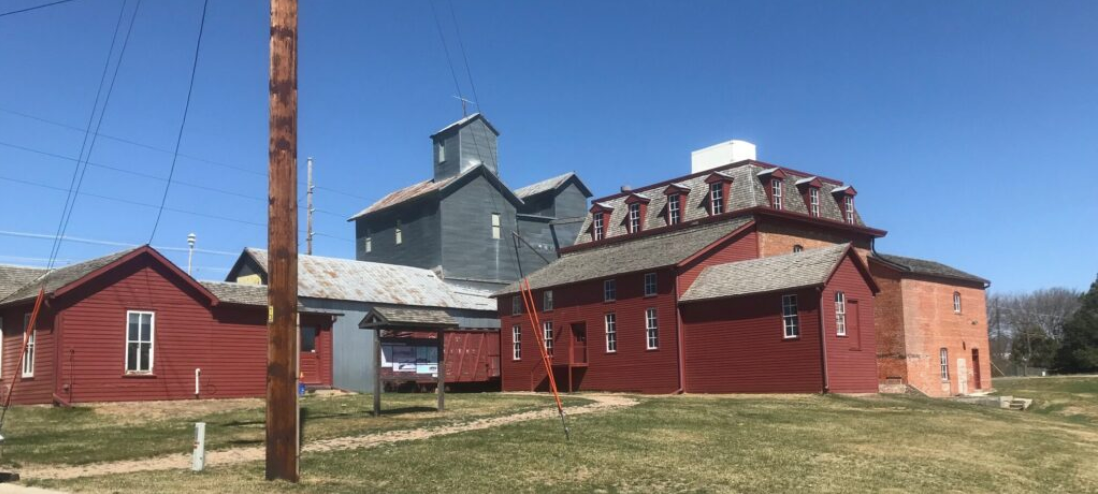 A portion of the historic Neligh Mill will be torn down — the tall, tin corn elevator and tin-sided warehouse. But the oldest portions will remain, including the brick mill and wheat elevator at right. (Courtesy of Roxanne McNally/Antelope County Historical Society)