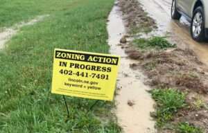 A “zoning action in progress” sign sits along First Street in Lincoln, where a housing development recently got the OK from the City Council. (Paul Hammel/Nebraska Examiner)