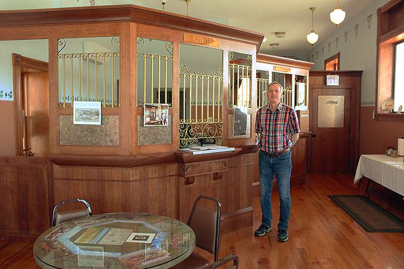 Bankery owner Tony Mahoney stands in front of the teller windows that were recreated during a 15-year restoration of the Dorrance State Bank. Photo by Cristina Janney / Hays Post<br>
