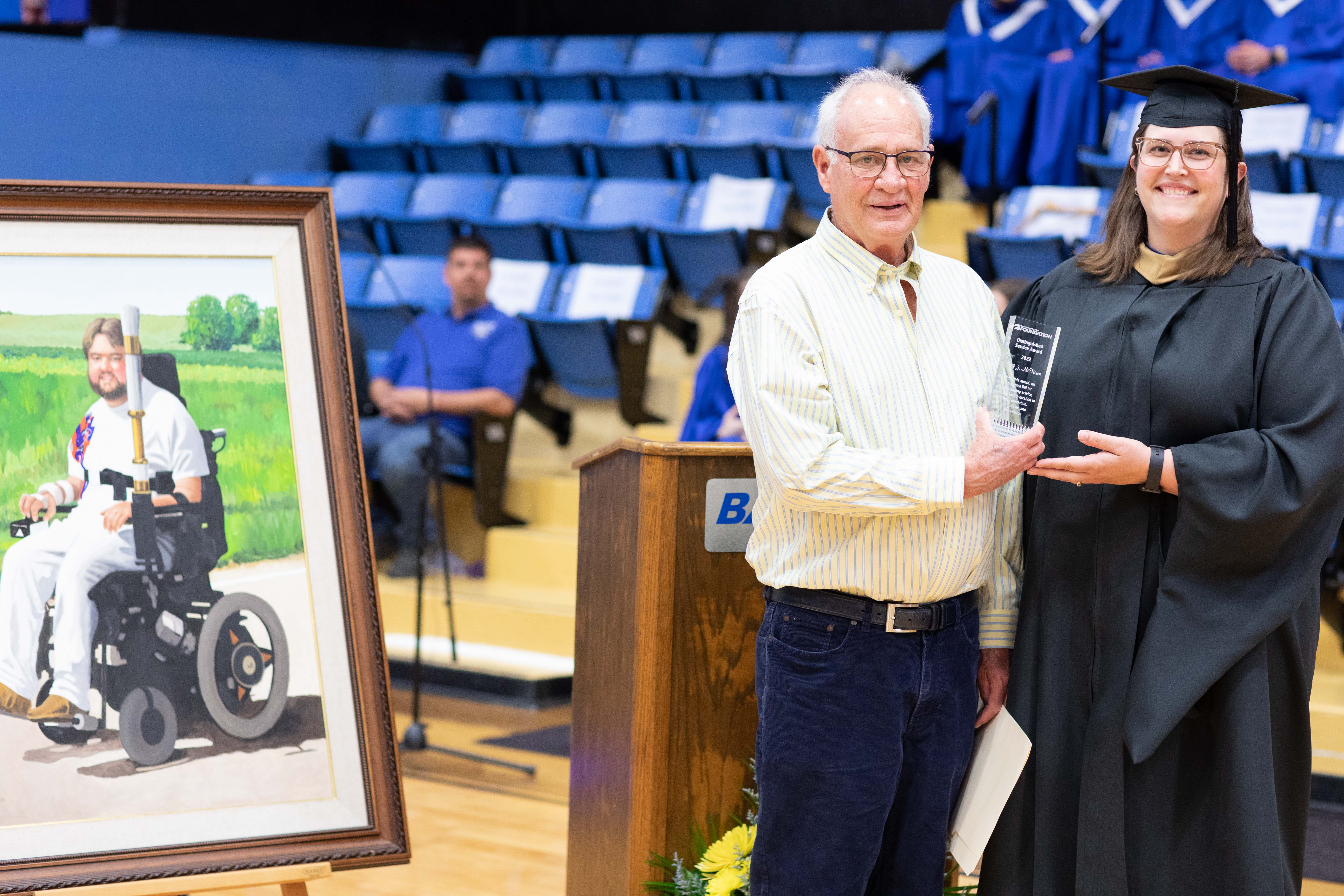 David McKown accepts the Distinguished Instructor Award on behalf of his late brother Bill McKown from Executive Director of Institutional Advancement Lindsey Bogner Friday night at the 52nd annual Barton Community College commencement.