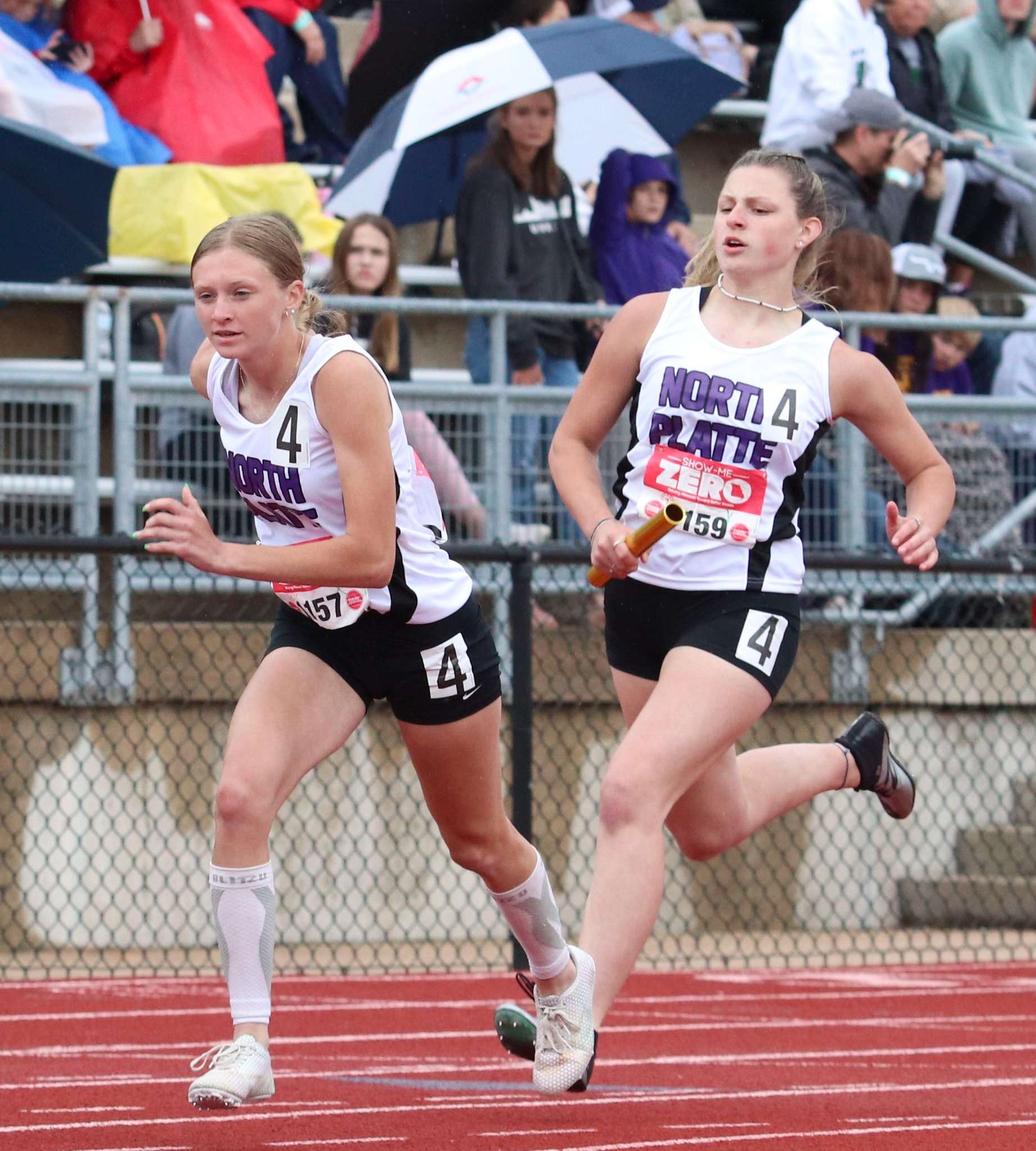 Olivia Rogers (left) completes a relay exchange with Kalli Schuster (right) at state track in Jefferson City. Photo by Tanner Cobb - Platte County Citizen.