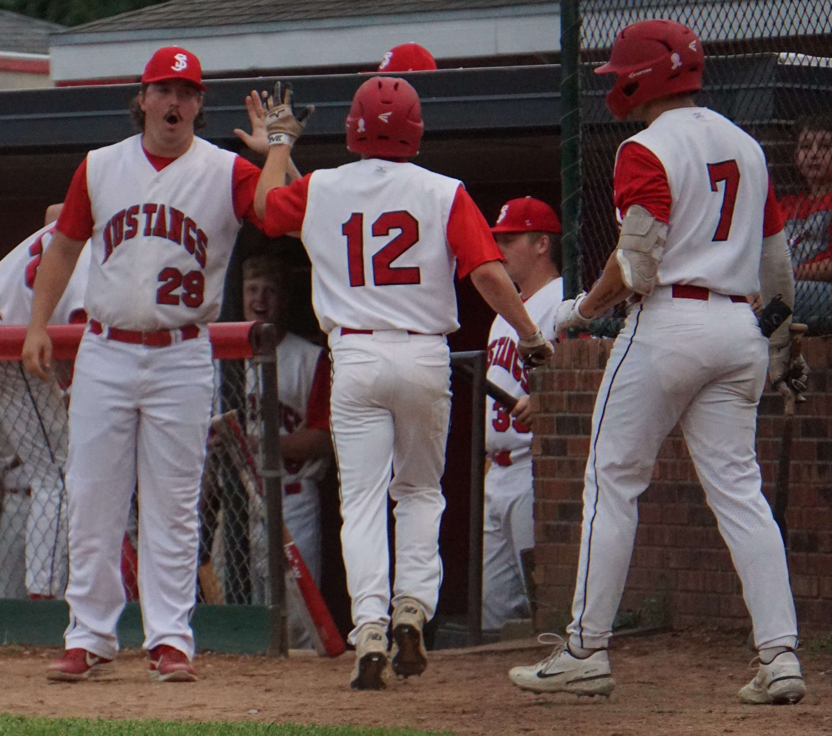 Noah Bodenhausen (12) receives high fives as he makes his way back to the dugout.