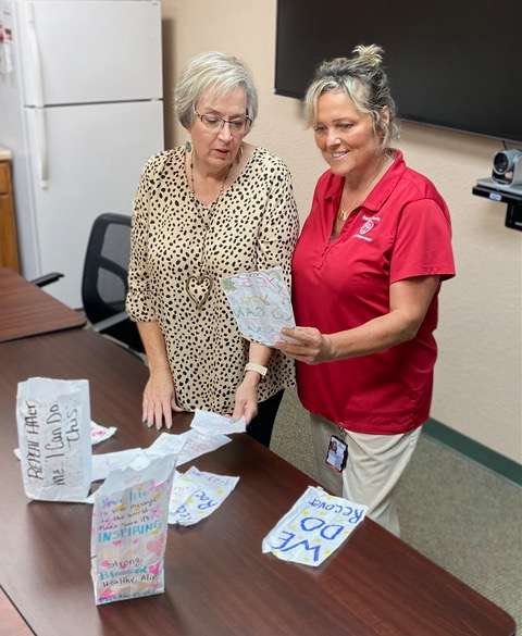 Julie Kramp, left, and Amy Ferguson review some positive messages that were featured at last year’s Recovery Out Loud in preparation for this year’s event.