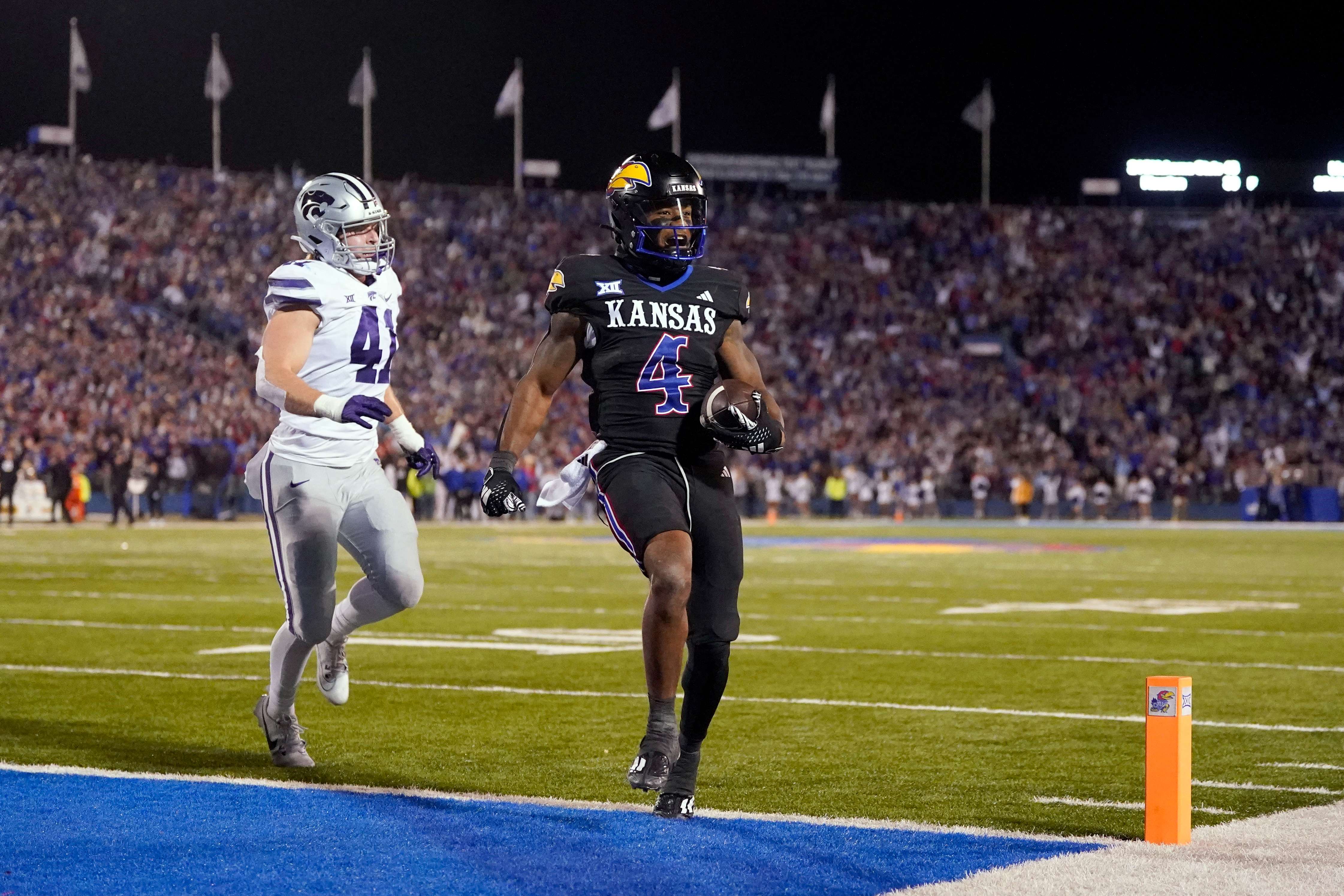 Kansas running back Devin Neal (4) is chased into the end zone by Kansas State linebacker Austin Moore (41) to score a touchdown during the first half of an NCAA college football game Saturday, Nov. 18, 2023, in Lawrence, Kan. (AP Photo/Charlie Riedel)