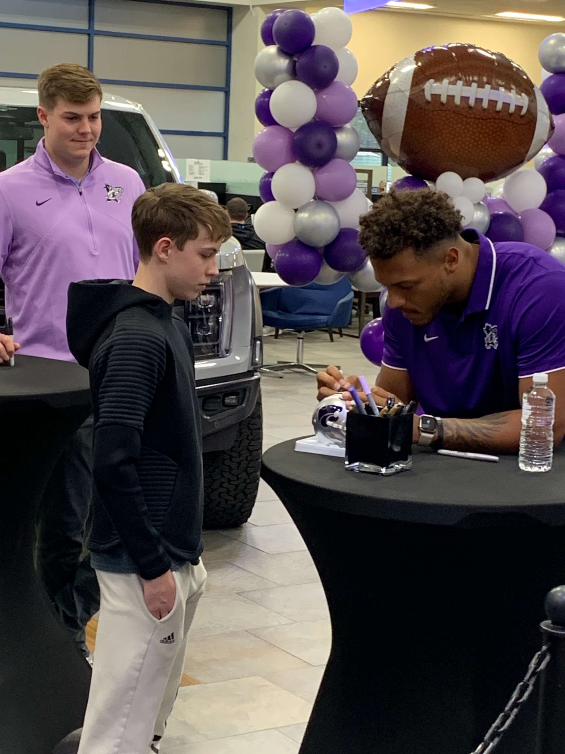 <b>Adrian Martinez autographs a miniature K-State helmet.</b>