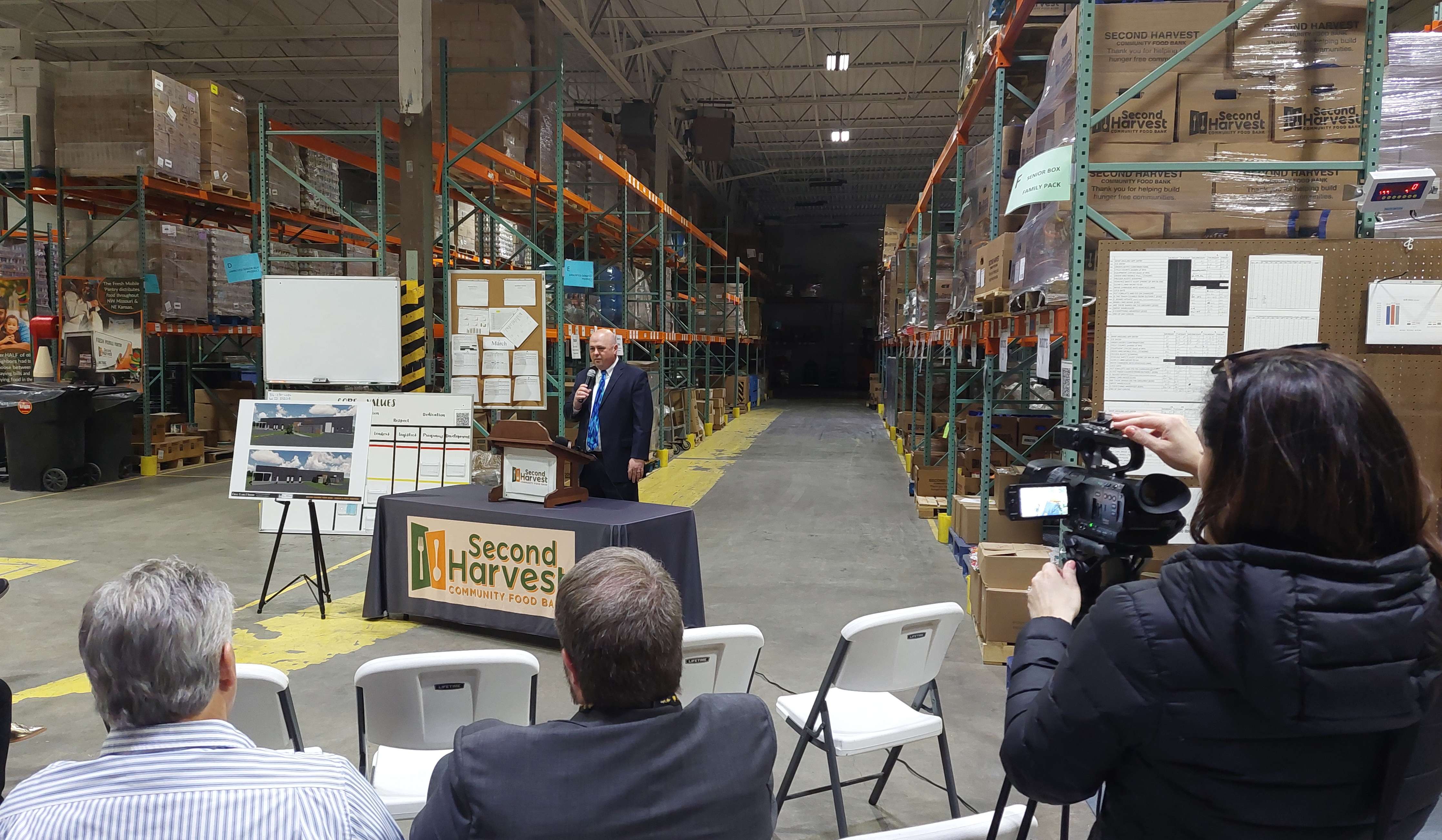 Second Harvest Community Food Bank CEO Chad Higdon speaks to a crowd gathered in the workshop at Second Harvest celebrating a grant that will help expand the food banks workspace/ Photo by Matt Pike
