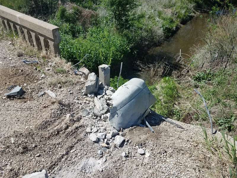 <b>The concrete bridge railing stopped the car from going into the creek below.</b>