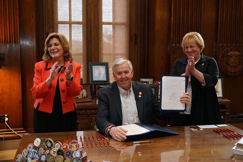 Rep. Brenda Shields&nbsp; of St. Joseph (left) applauds at the bill signing with Gov. Mike Parson and Senate sponsor, Sen. Kara Eslinger of Wasola/Photo courtesy of Gov. Parson's office