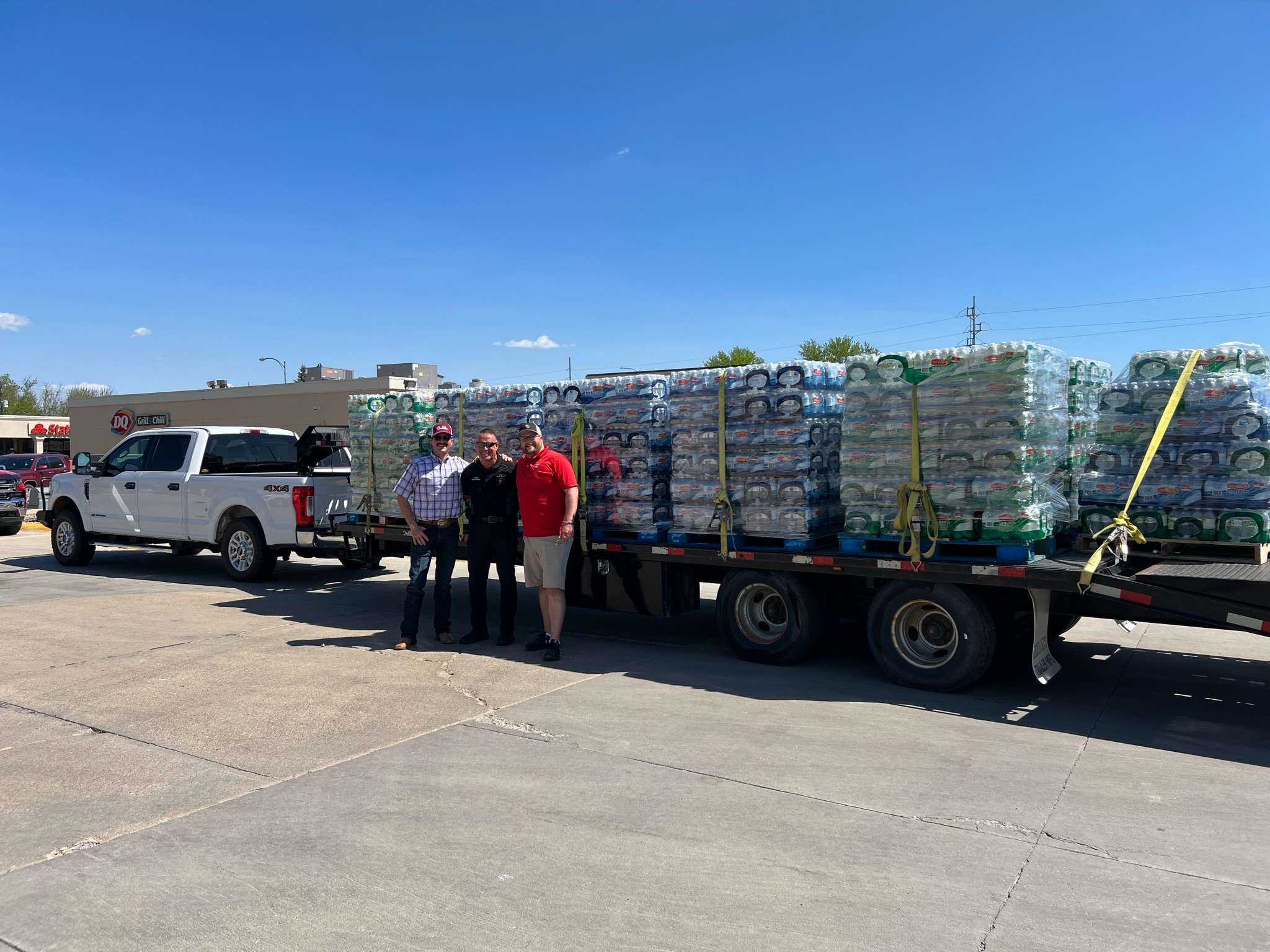 Chase Dodson, North Platte Fire Chief Dennis Thompson and Jordan Boston stand in front of trailer loaded with donated pallets of bottled water