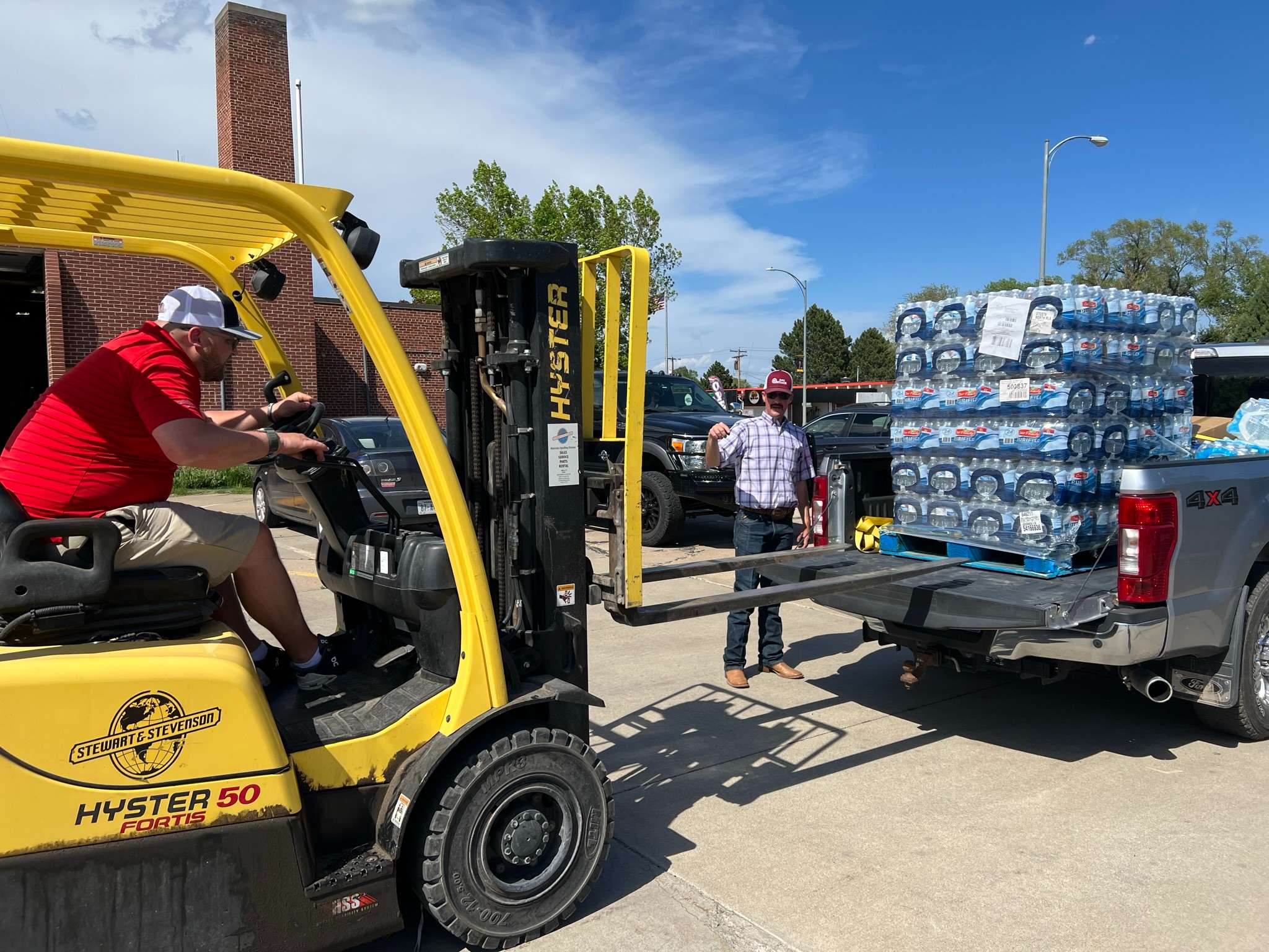 Jordan Boston loading pallet of bottled water on to a rural fire department volunteer pickup with the direction of Chase Dodson