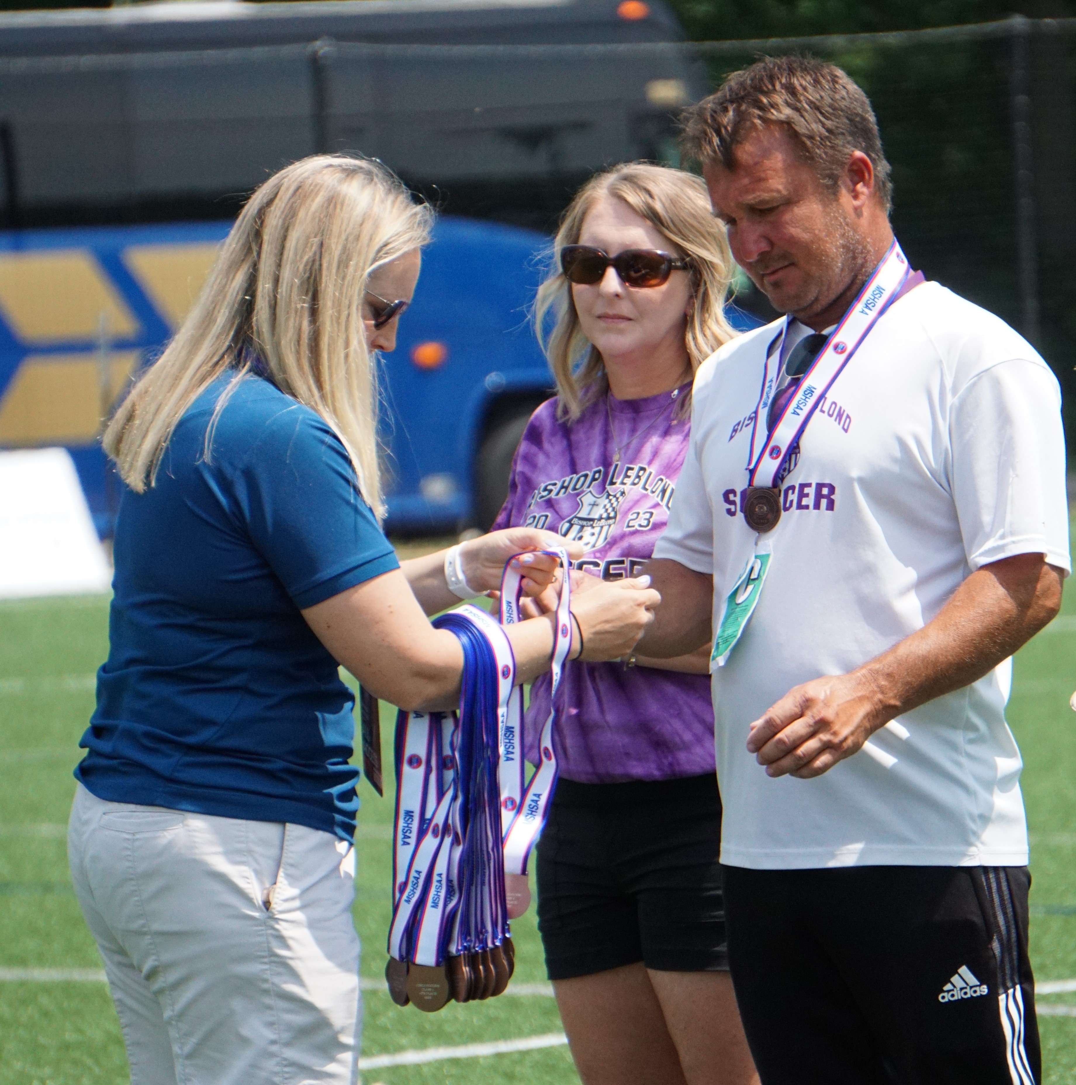 Coach Chad Thompson receives the medals for the team.