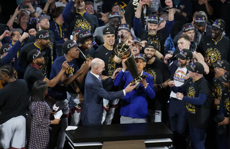 Denver Nuggets players, coaches and owners pose with the Larry O'Brien NBA Championship Trophy after their victory over the Miami Heat in Game 5 of basketball's NBA Finals, Monday, June 12, 2023, in Denver. (AP Photo/David Zalubowski)