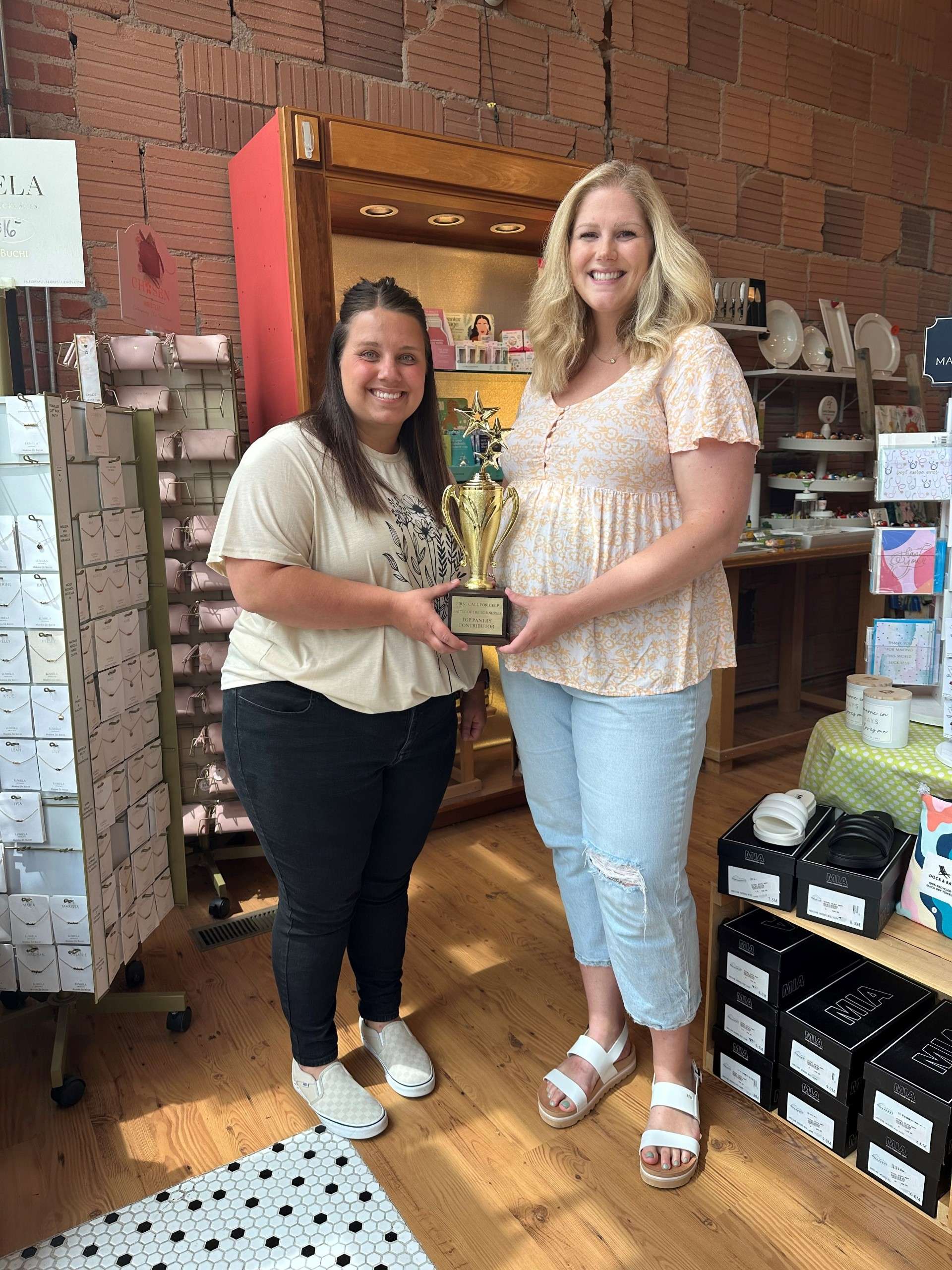 Macey Pfeifer, First Call for Help executive director, awards the first place Battle of the Businesses trophy to Sarah Cearley-Windholz, owner of Simply Charmed. Courtesy photo&nbsp;