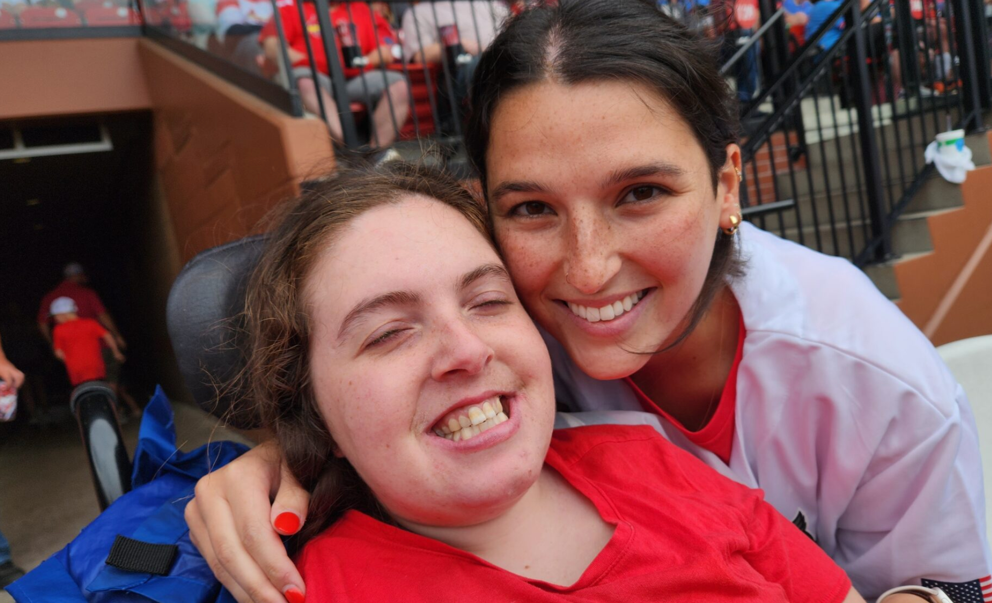 Lilly Opinsky, who has Rett disease, with her personal care attendant, Megan Wallis, at a Cardinals game this year. The family uses a program called self-directed supports to pay caretakers (Photo submitted).
