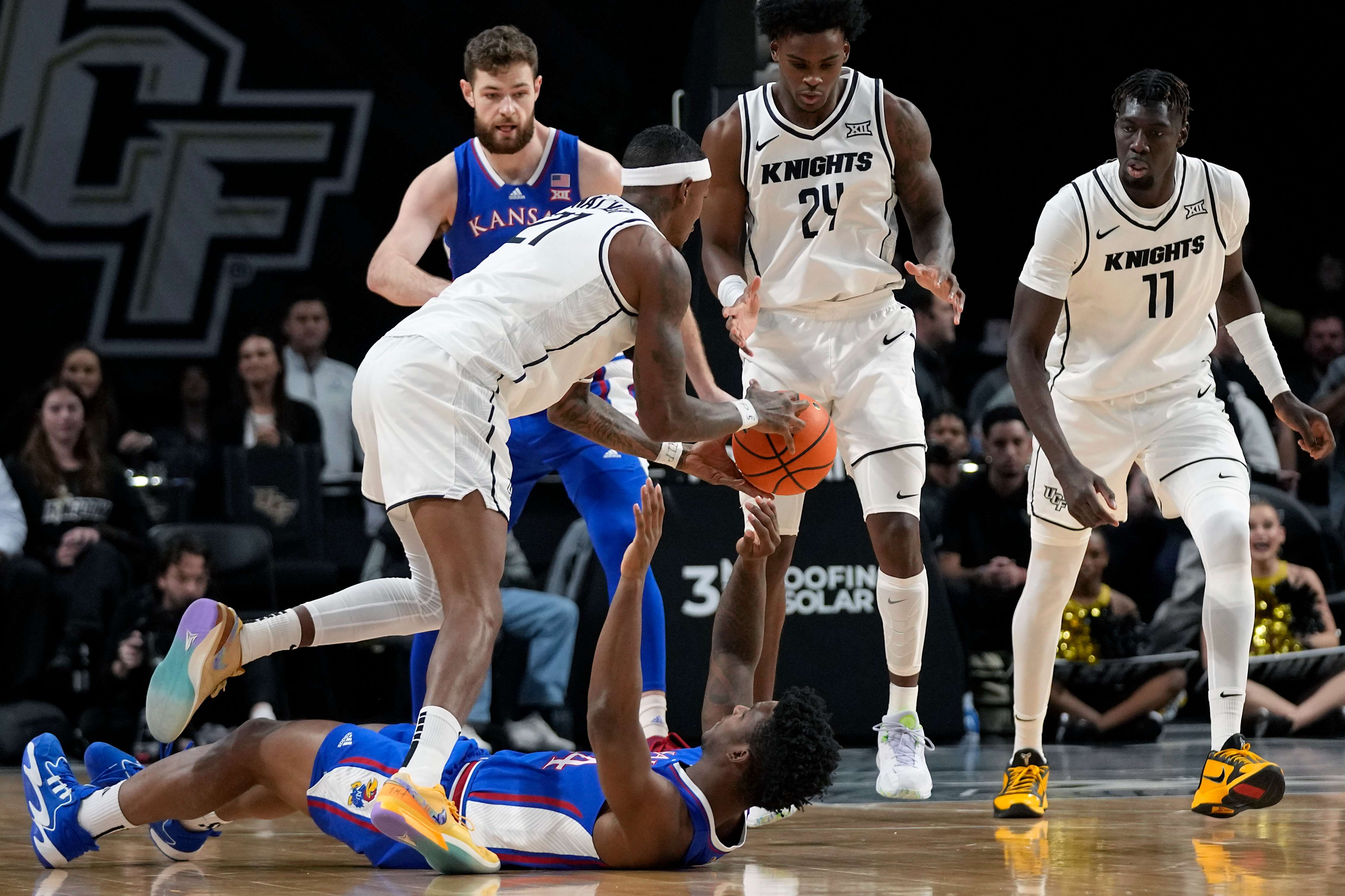 Central Florida forward C.J. Walker, front left, grabs the ball from Kansas forward K.J. Adams Jr. as he falls backward during the first half of an NCAA college basketball game, Wednesday, Jan. 10, 2024, in Orlando, Fla. (AP Photo/John Raoux)