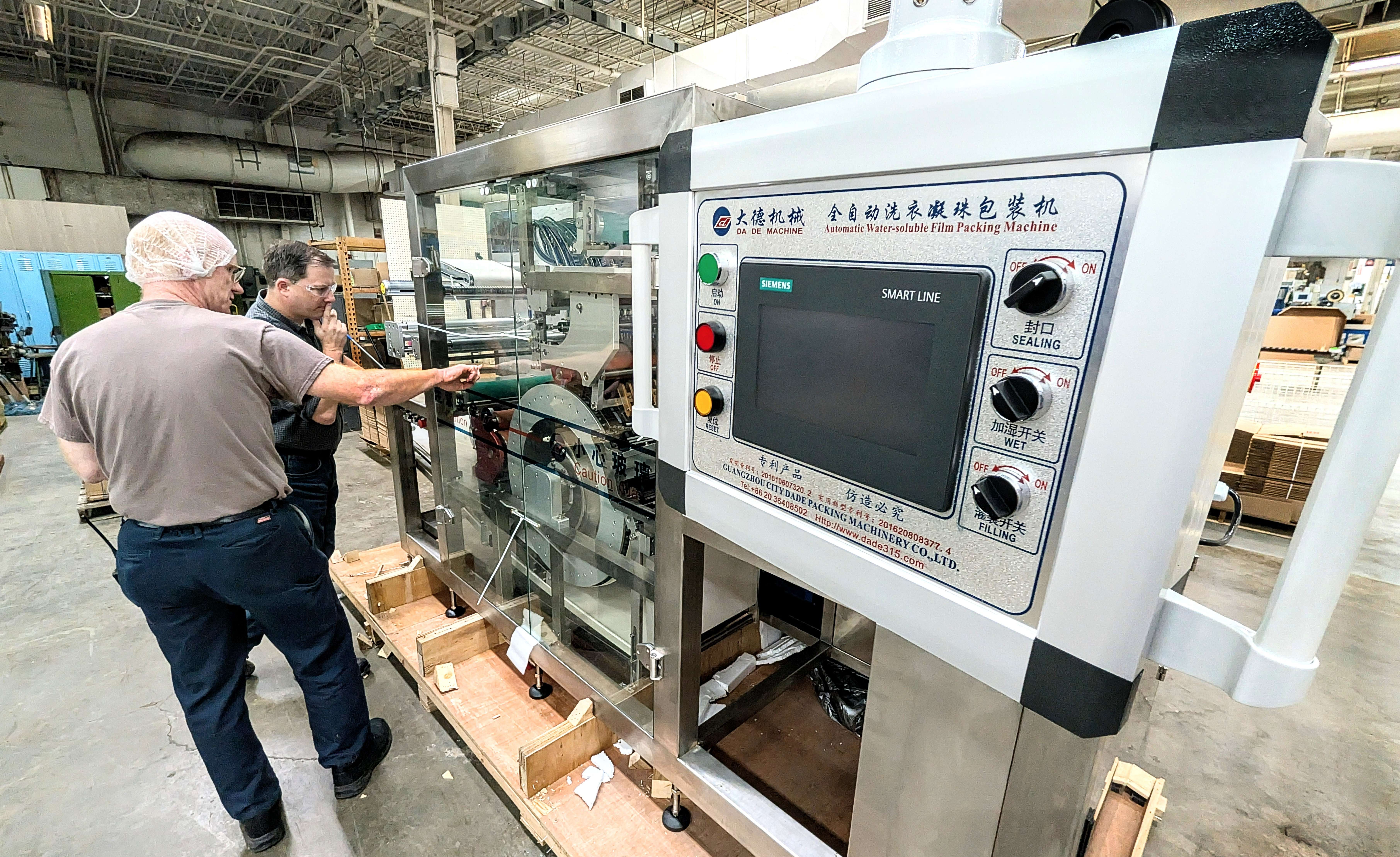 Fuller Industries Inc.’s machine technician Jay Scheck and process engineer James Chipman inspect the company’s new monopod-making machine last week. The device can produce 400 pods per minute as Fuller ups its pod production.