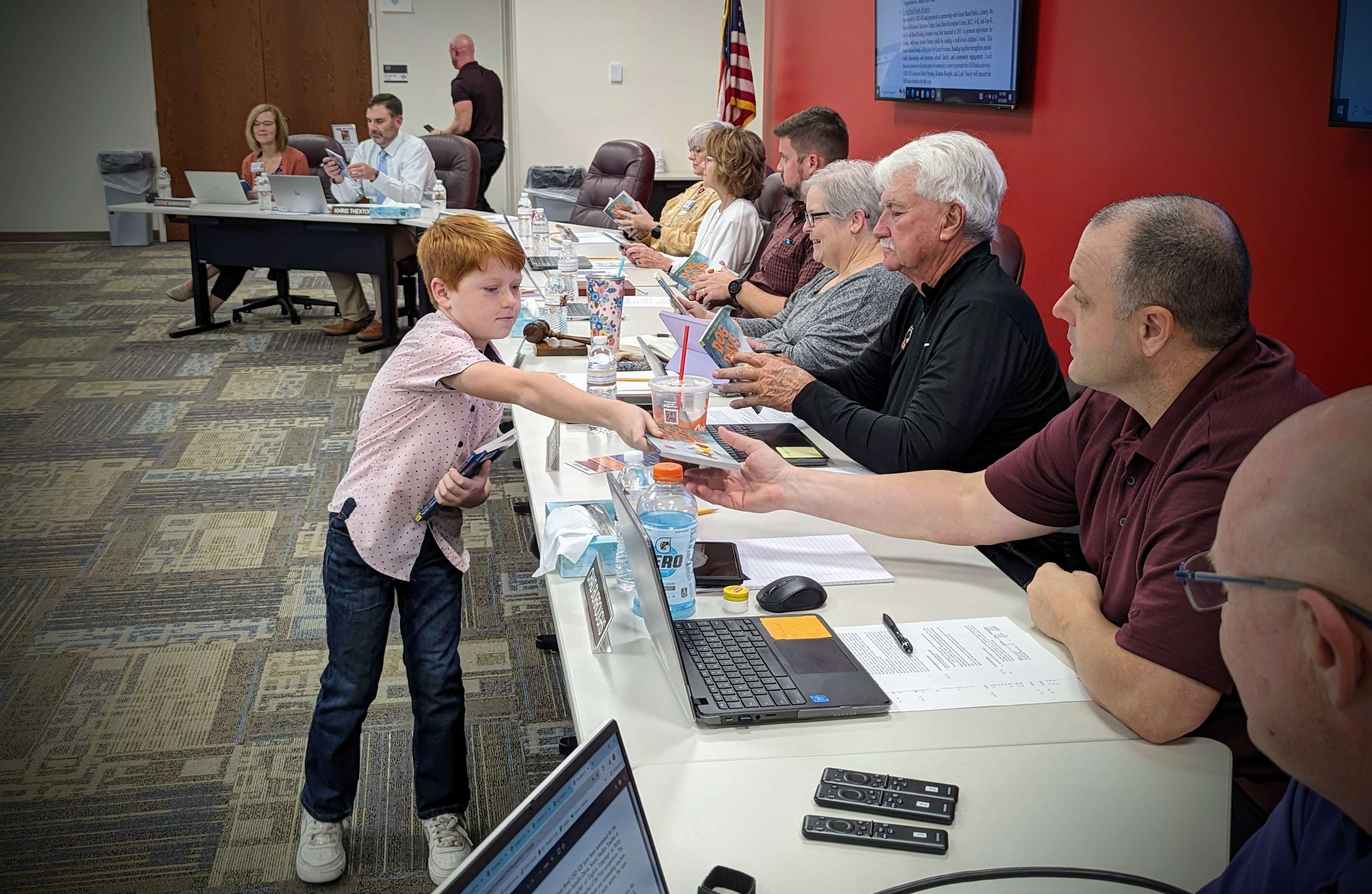 Lincoln Cale, a 4th-grade student at Jefferson Elementary, presents Board of Education members with copies of the 2025 GB Reads book, Dog Days by Karen English, at the Nov. 11 Board of Education Meeting. Lincoln introduced the main character, Gavin, by reading a segment of the book, giving board members a glimpse into Gavin’s journey as the new kid at Carver Elementary, where he learns about friendship, responsibility, and making good choices.