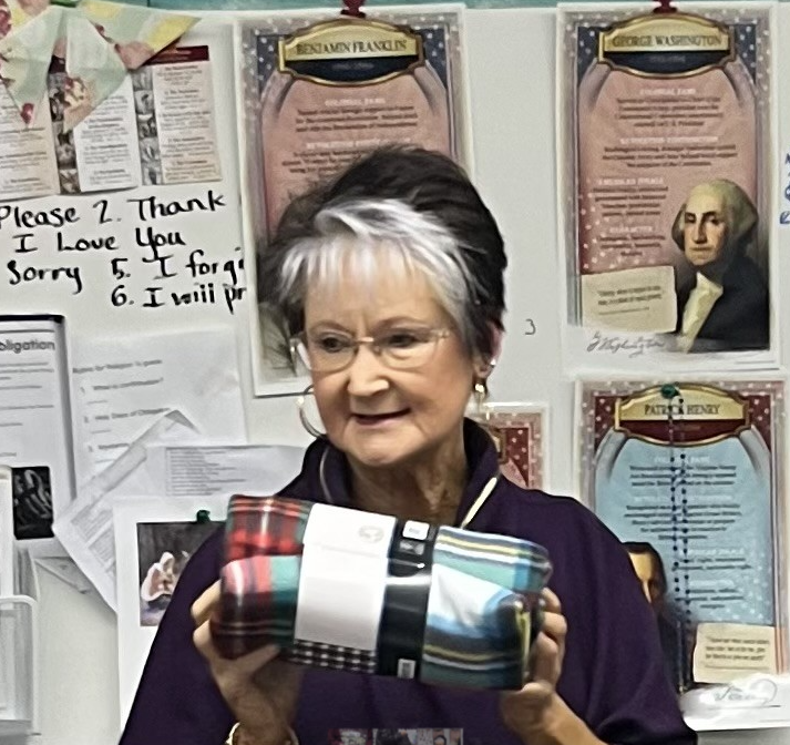 Sandra Burton purchased 22 Christmas blankets as reward and reminder to St. Joseph students in Ellinwood of their good deed.