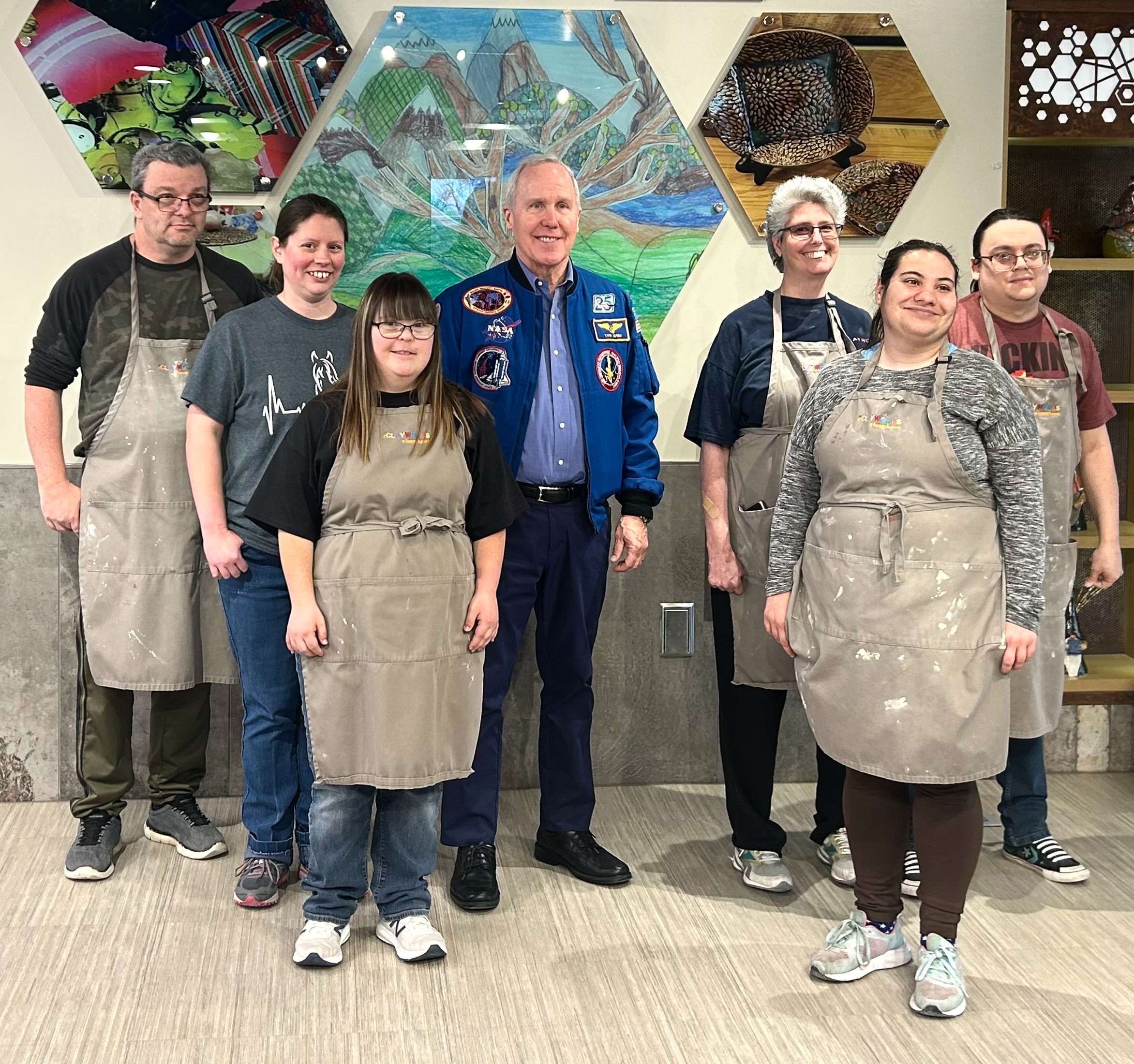 Clients at The Clayworks at Disability Supports taking a photo with Space Shuttle Astronaut Tom Jones on Friday, Feb. 2.&nbsp; Jones visited with the clients and signed their artwork that&nbsp; is inspired by the Kansas Cosmosphere. Photo by Emmie Boese.&nbsp;