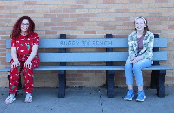 Sixth graders Lily Browning (left) and Kylee Smith (right) sit on the Buddy Bench on the Graber Elementary playground on Thursday, Feb. 8, 2024. The project was led by Smith and the bench was placed on the Graber Elementary Playground on Oct. 2, 2023. Photo by Emmie Boese. 