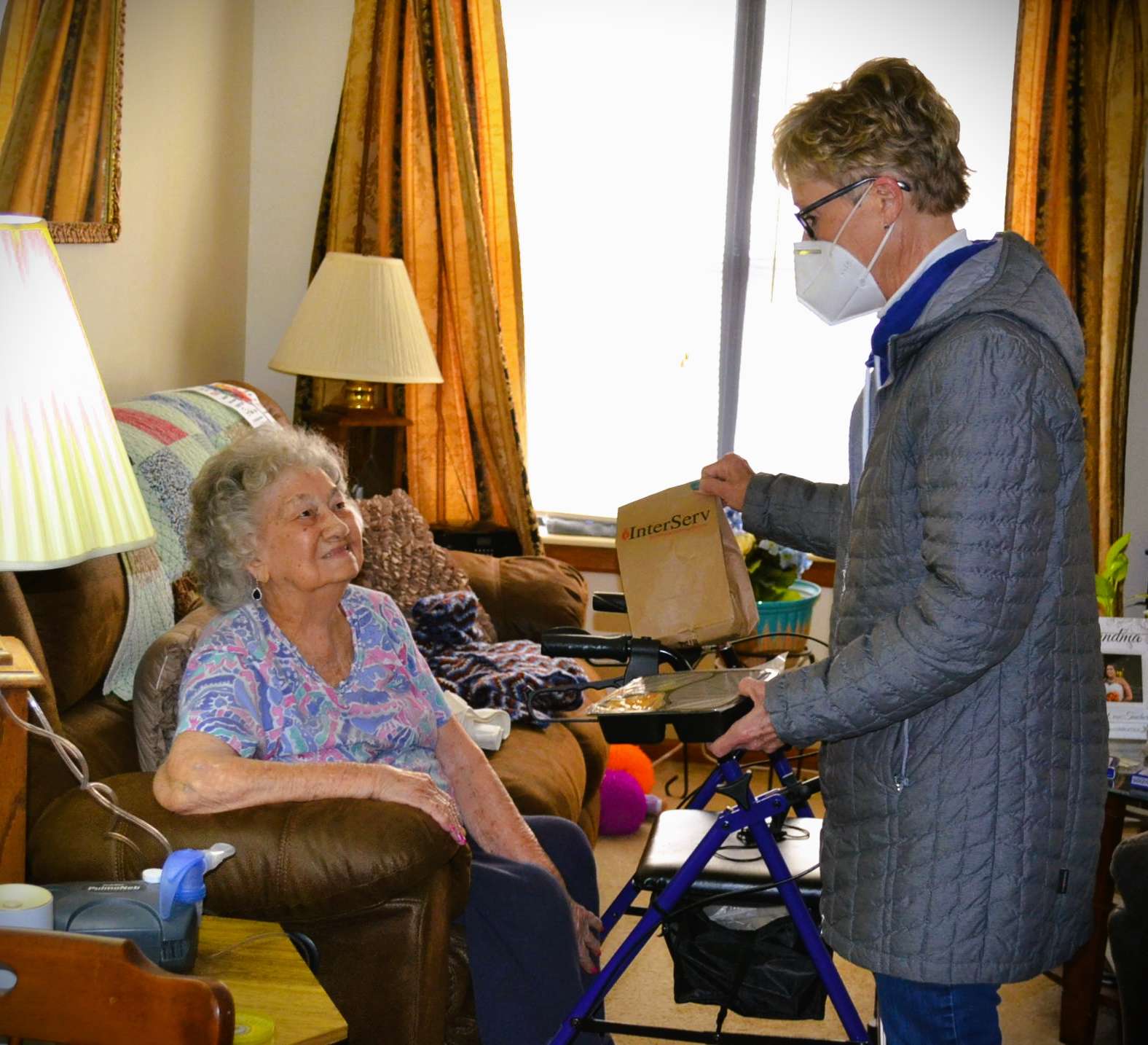 InterServ volunteer Ann hand delivering to client in home/ Photo courtesy of InterServ