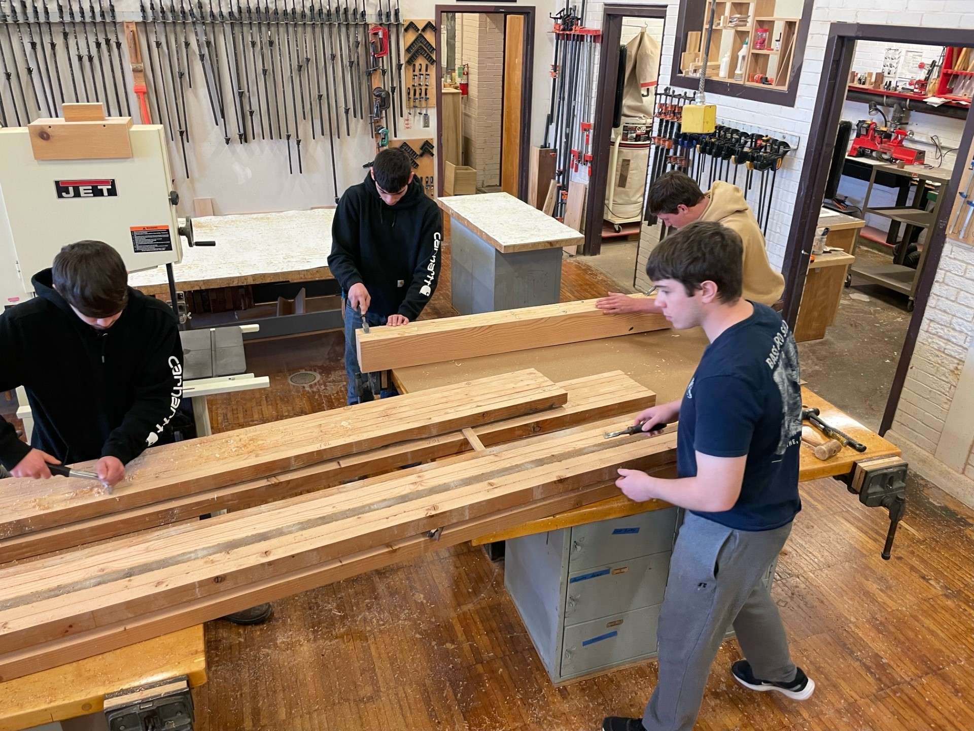 Travis Straub's students scrape glue from the faux beam to be installed at the church.