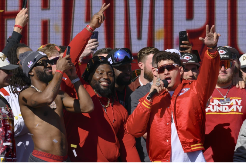 Kansas City Chiefs quarterback Patrick Mahomes, right, tells the crowd the Chiefs want to win another Super Bowl next season, during their victory rally in Kansas City, Mo., Wednesday, Feb. 14, 2024. The Chiefs defeated the San Francisco 49ers Sunday in the NFL Super Bowl 58 football game. (AP Photo/Reed Hoffmann)