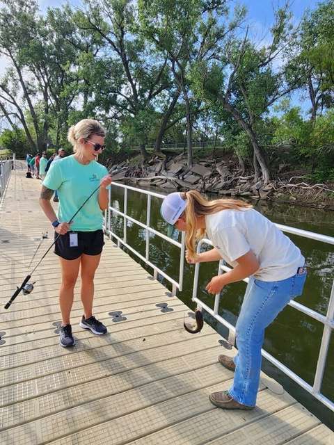 Blakelee Cooper, left, and Jessa Chapman participate in a recent Juvenile Services (JS) Life Skills fishing class at Veterans Lake in Great Bend where they reeled in a catfish. Most Life Skills classes relate to career and home but leisure courses also are offered. Cooper is the community case manager at JS and Chapman is a summer assistant at the Kansas Department of Wildlife and Parks (KDWP). They joined several JS clients who learned some of the finer points of fishing from Instructor Travis Riley, fisheries biologist for the Ellsworth District of KDWP. JS is recruiting volunteers to lead classes. For more information, contact Jack Bowman, JS program advocate, by calling 620-793-1930.