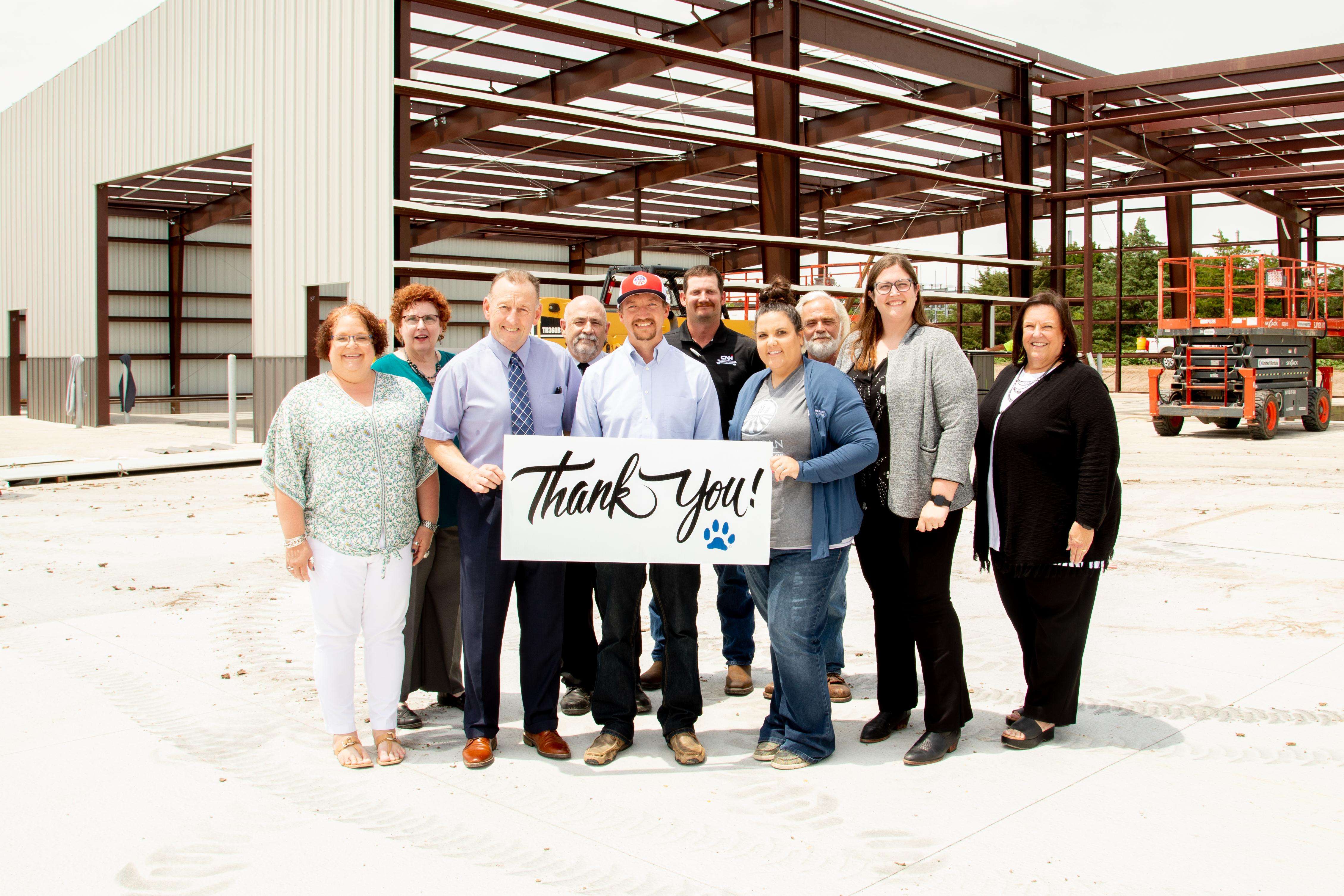 Representatives from American Plains Co-op join the Barton Community College team during the construction of the new Ag and Transportation Complex to mark the beginning of a new partnership with a three-year leadership pledge to the Barton Foundation. (Front row, from left) Barton Executive Director of Agriculture and Industry Education Mary Foley, Former Barton President Dr. Carl Heilman, CEO of American Plains Co-op Bryan Moser, American Plains Co-op Communications and Brand Programs Coordinator Cammie Vaupel, Barton Executive Director of Institutional Advancement Lindsey Bogner, Dean of Workforce Training and Community Education Dr. Kathy Kottas, (Back row, from left) Vice President of Instruction Elaine Simmons, Vice President of Administration Mark Dean, CNH Trainer Mark Bogner, and Agriculture Instructor and Coordinator Dr. Vic Martin.
