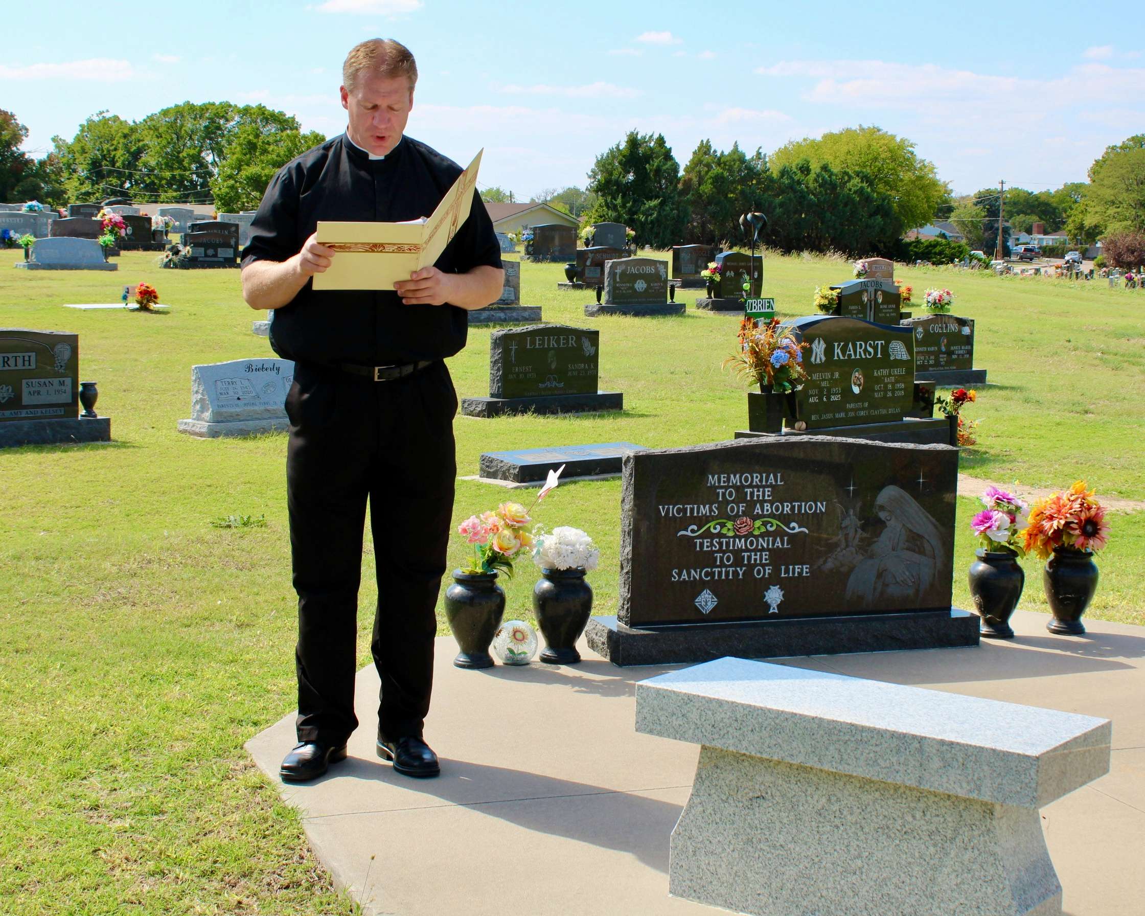 Fr. Nick Parker of Immaculate Heart of Mary Catholic Church in Hays reading scripture at the St. Joseph Cemetery. Photo by Tony Guerrero/Hays Post
