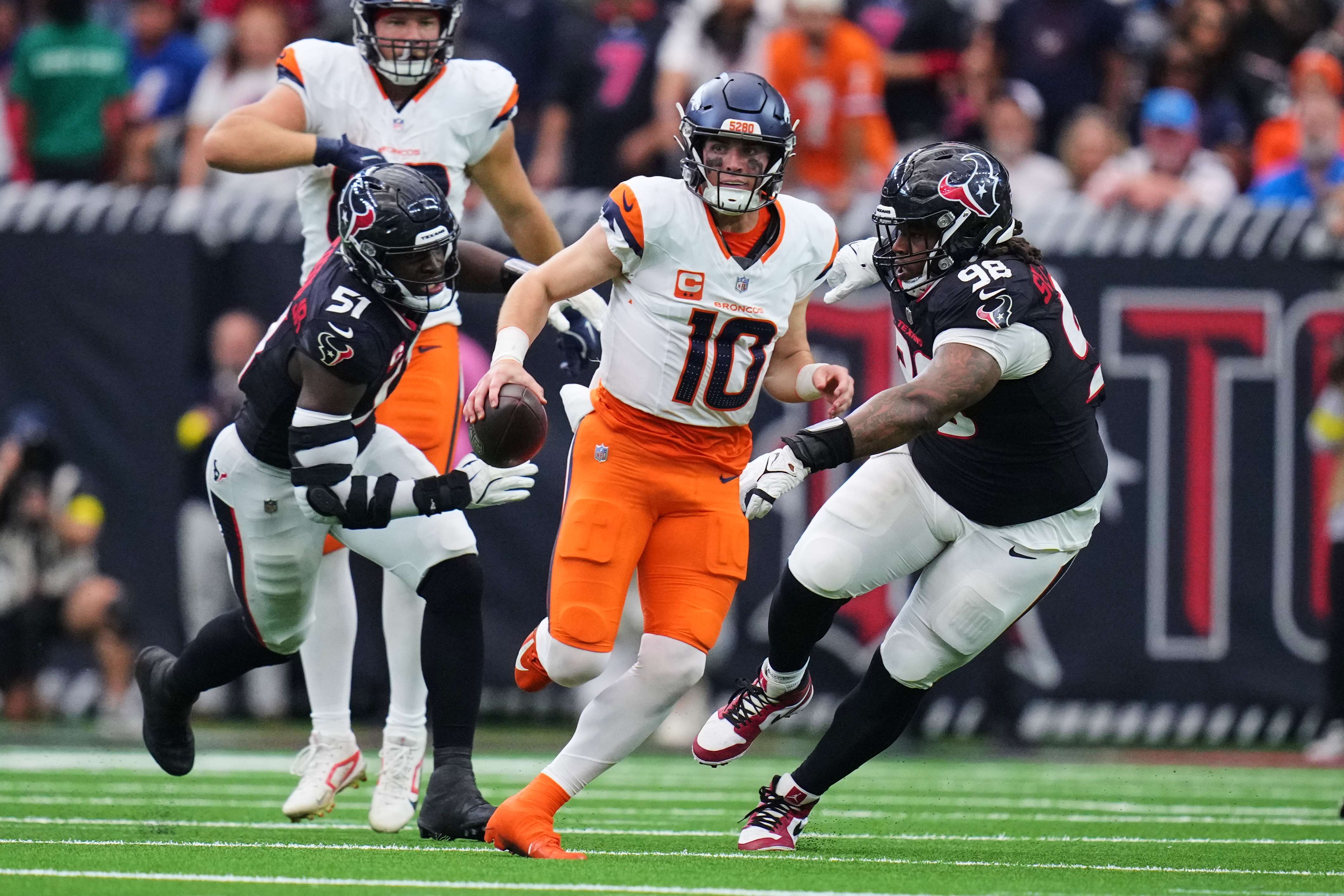 Denver Broncos quarterback Bo Nix (10) escapes pressure from Houston Texans defensive end Will Anderson Jr. (51) and Tim Settle Jr. (98) as Nix runs the ball for a long gain in the second half of an NFL football game Sunday, Nov. 2, 2025, in Houston. (AP Photo/Eric Gay)