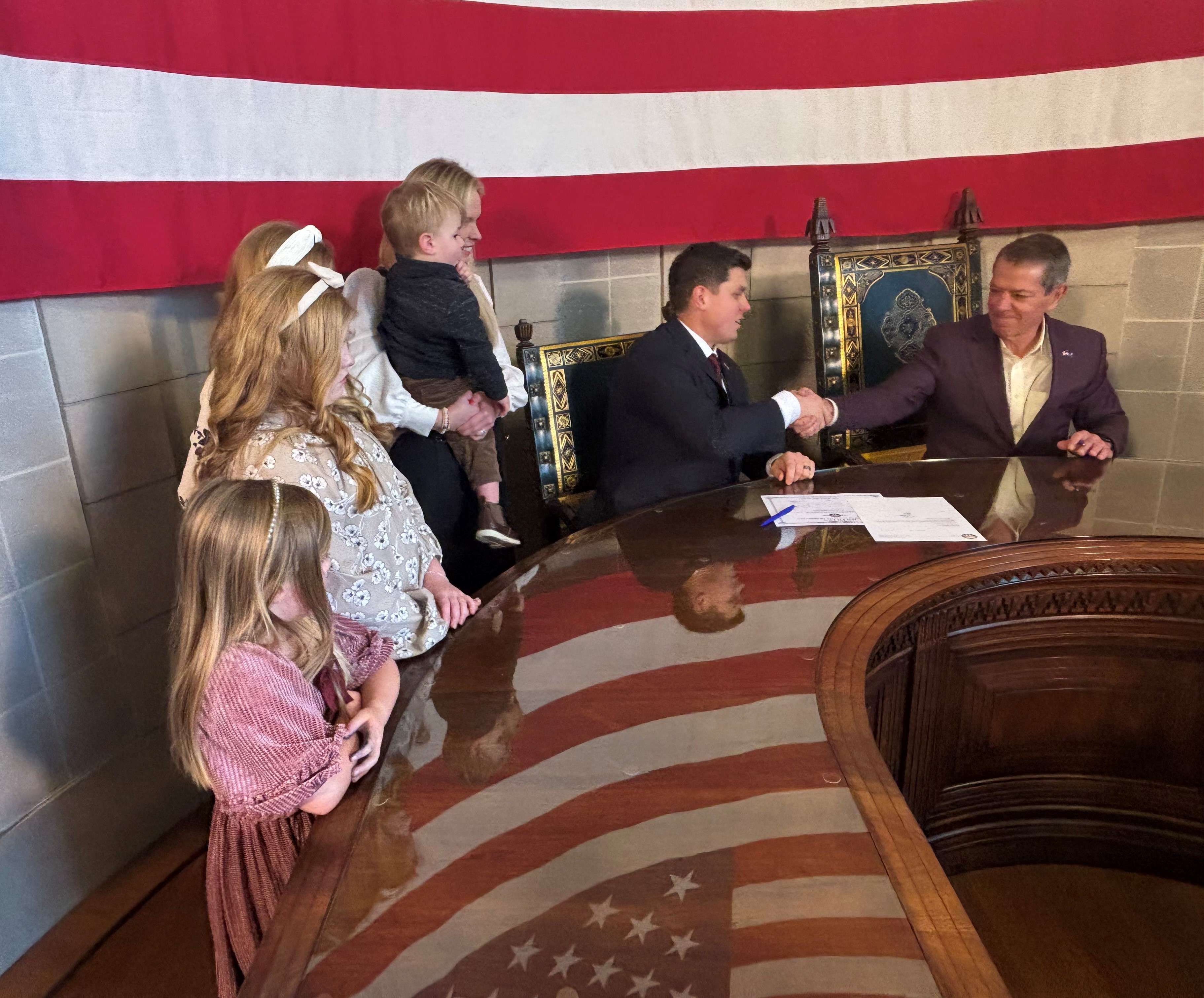 Spellerberg with his family and Governor Jim Pillen shake hands during the swearing in ceremony for Nebraska State Treasurer. (Courtesy Nebraska State Treasurers Office)
