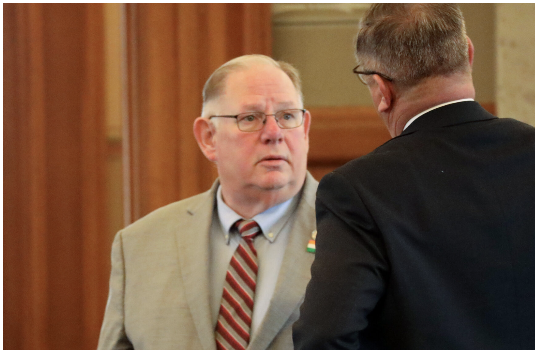 Kansas House Speaker Dan Hawkins, a Wichita Republican campaigning for state insurance commissioner, removed at least three House Republicans from committee chairmanships for declining to sign a petition allowing a special session of the Kansas Legislature to consider President Donald Trump's request to redraw the state's U.S. House district boundaries to improve odds of defeating Democratic U.S. Rep. Sharice Davids in the November 2026 election. This March 2025 image is of Hawkins speaking to a GOP colleague. (Photo by Grace Hills/Kansas Reflector)