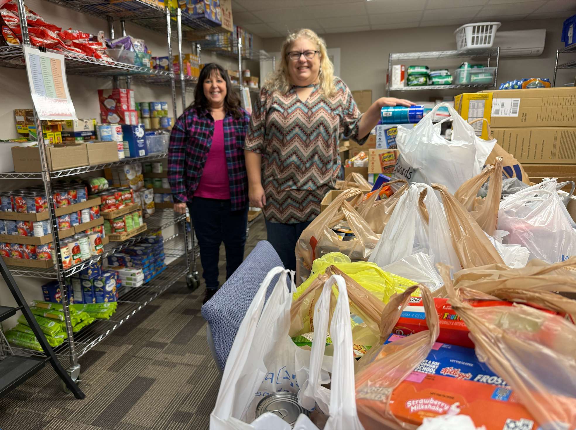 Cristina Janney, Hays Post editor, with Laura Shoaff, First Call for Help client services specialist, as the Post and Eagle Radio deliver food gathered from their food drive on Wednesday.