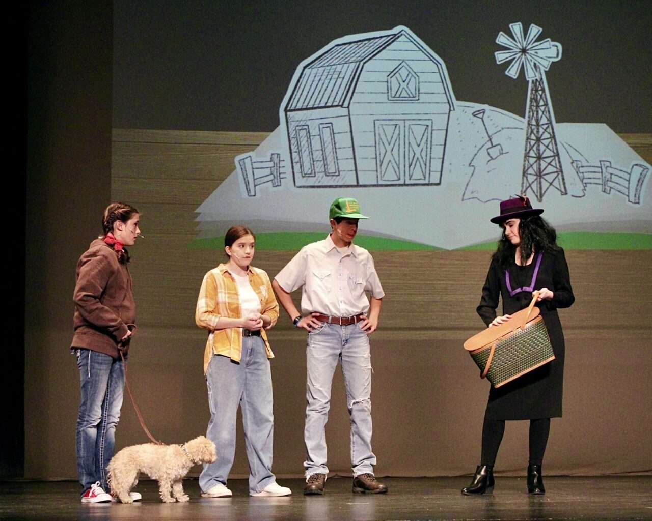 Grace Schmeidler as Dorothy Gale with several supporting characters and Toto on stage for "The Wizard of Oz" production. 