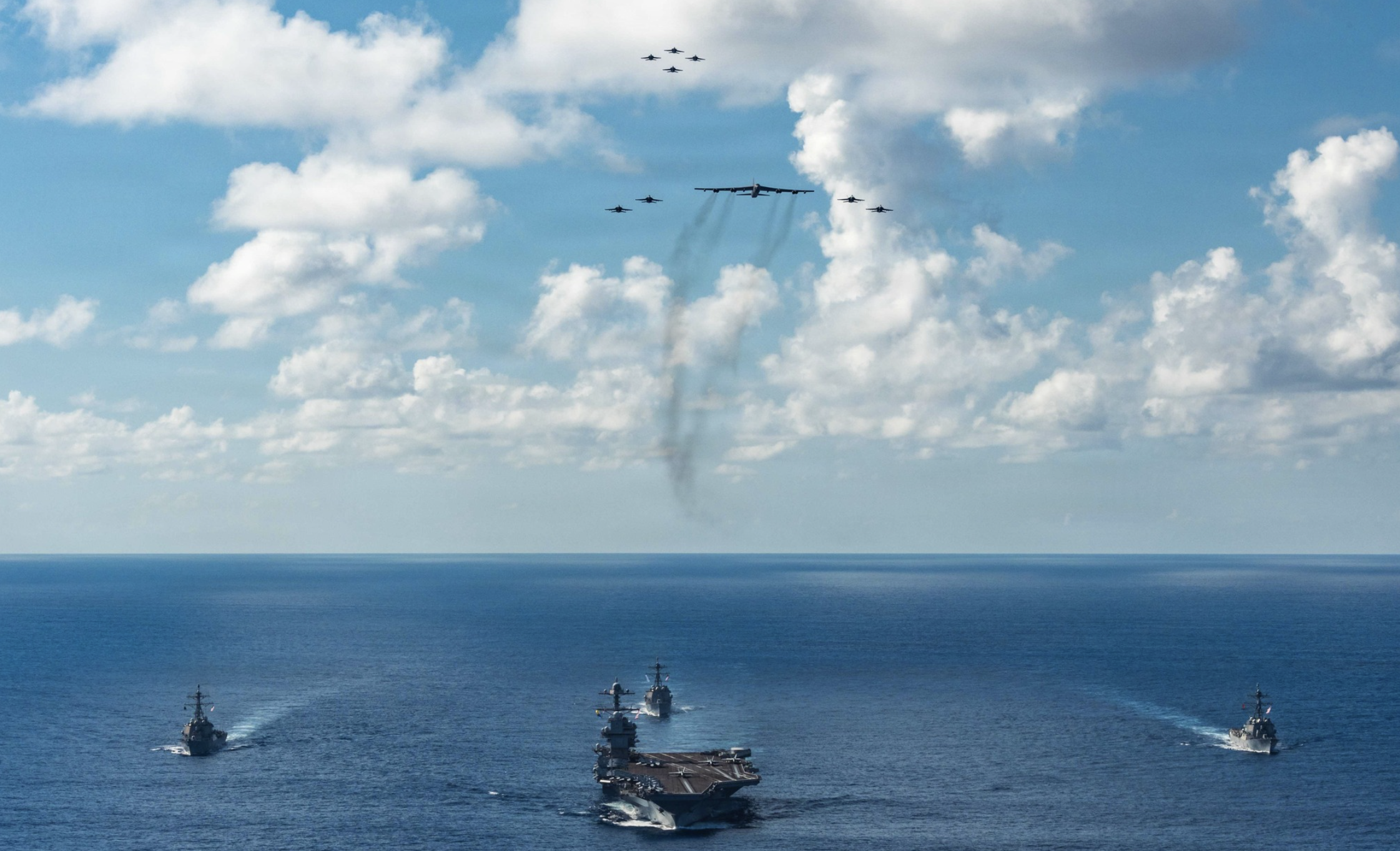 The U.S. Navy’s Gerald R. Ford Carrier Strike Group, including the flagship USS Gerald R. Ford (CVN 78), front, USS Winston S. Churchill (DDG 81), right, USS Mahan (DDG 72), left, USS Bainbridge (DDG 96), and embarked Carrier Air Wing Eight F/A-18E/F Super Hornets assigned to Strike Fighter Squadrons 31, 37, 87, and 213, operates as a joint, multi-domain force with a U.S. Air Force B-52 Stratofortress, Nov. 13, 2025. U.S. military forces, like the Gerald R. Ford Carrier Strike Group, are deployed in support of the U.S. Southern Command mission, Department of War-directed operations, and the President’s priorities to disrupt illicit drug trafficking and protect the homeland. -Photo by Petty Officer 3rd Class Gladjimi Basisage