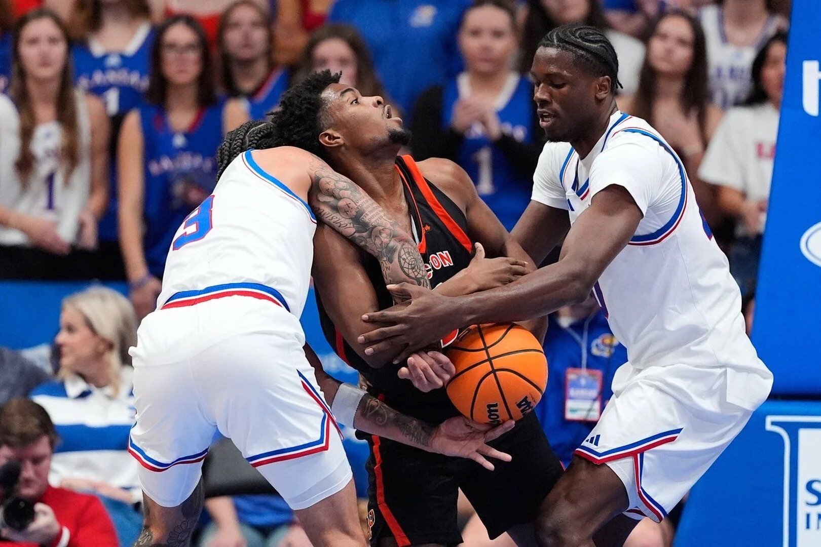 Kansas guard Tre White, left, and forward Flory Bidunga, right, try to steal the ball from Princeton guard Dalen Davis (22) during the first half of an NCAA college basketball game Saturday, Nov. 15, 2025, in Lawrence, Kan. (AP Photo/Charlie Riedel)