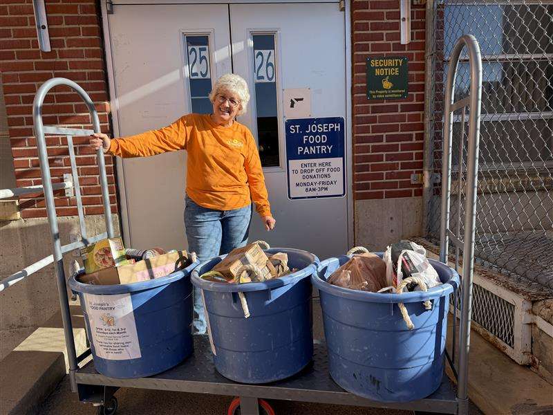 Renee Michaud of the St. Joseph Food Pantry accepting food from the Hays Post food drive on Thursday. 