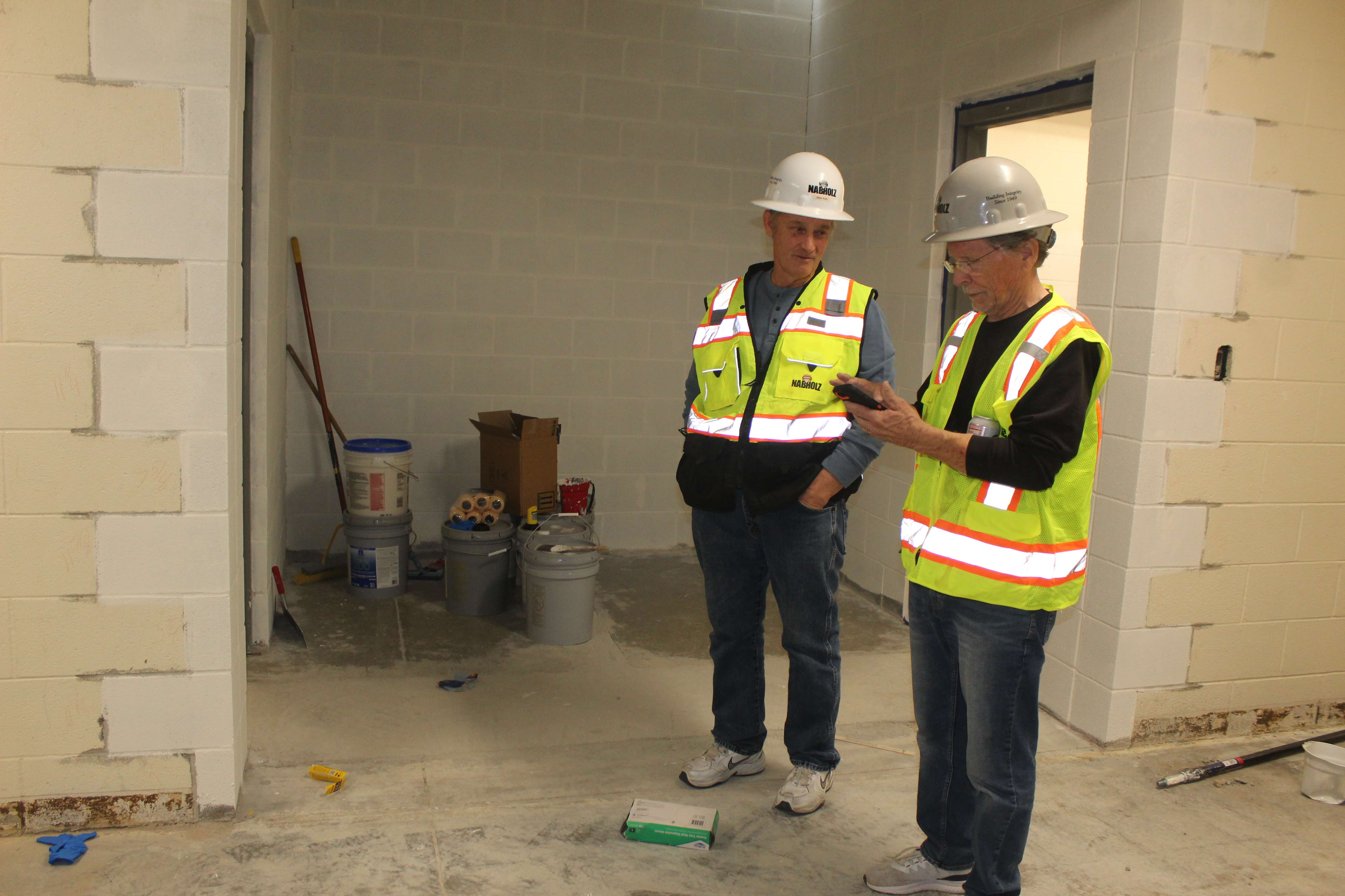 Hays USD 489 board member Allen Park, left, and board member-elect Craig Pallister, right, in front of new girls' and boys' restrooms that have been added to the Hays Middle School athletic wing.&nbsp;Photo by Cristina Janney/Hays Post