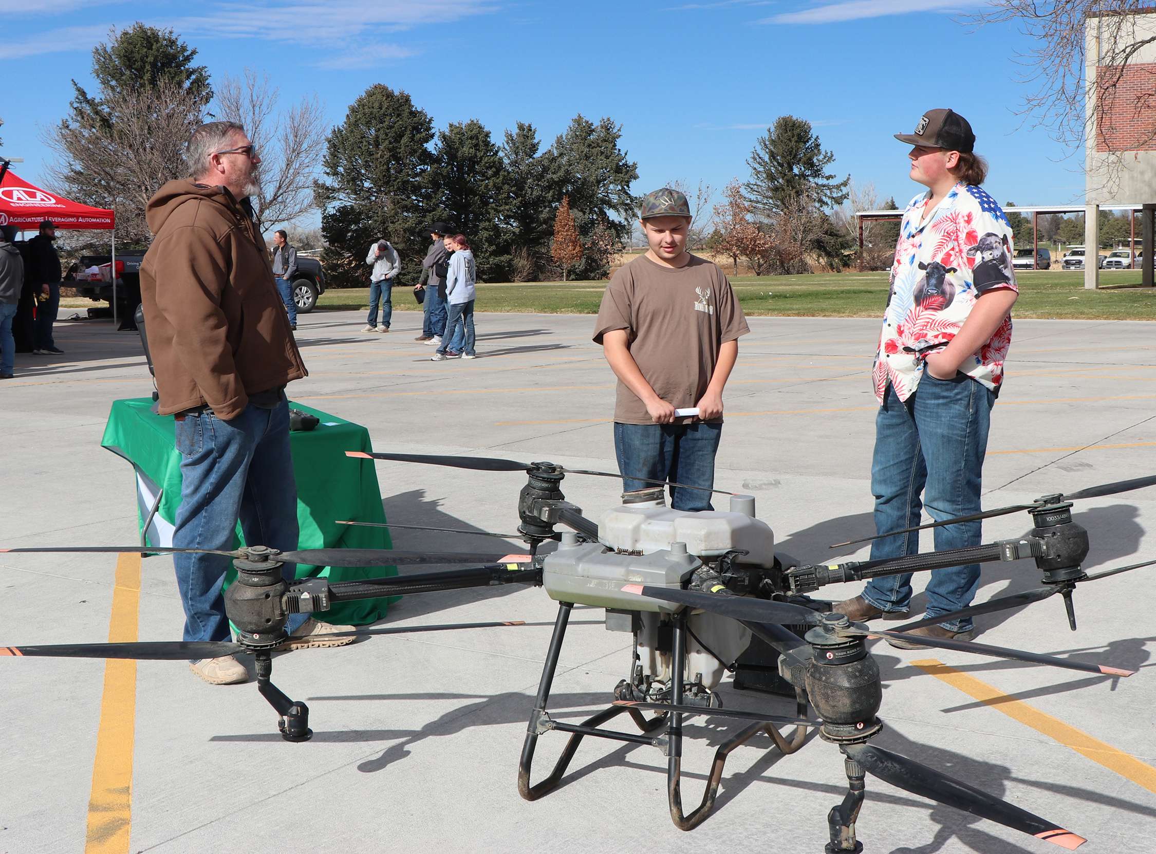 Freedom Crop Services owner Casey Jagers, left, talks with Alex Blake and Lane Hoerler, students at Bridgeport High School, about drones, spraying, and what it takes to be a drone pilot. Photo by Chabella Guzman