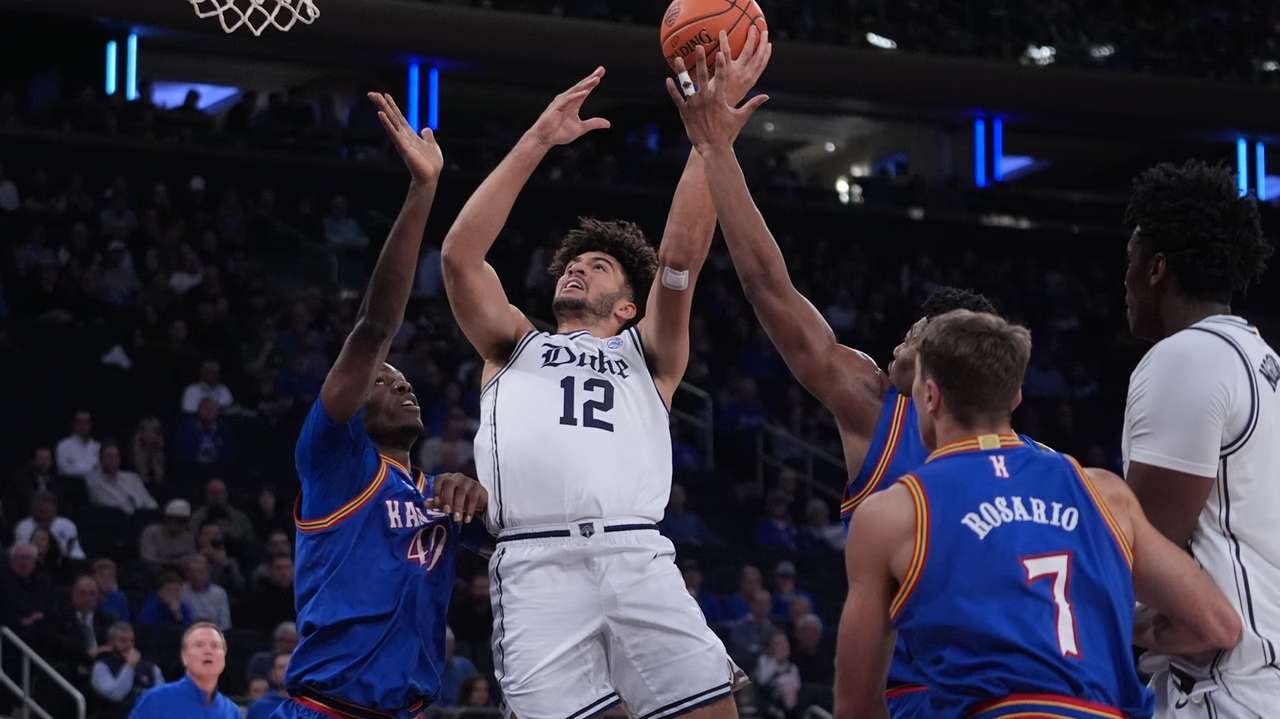 Duke's Cameron Boozer (12) drives past Kansas' Flory Bidunga (40) and Kohl Rosario (7) during the first half of an NCAA college basketball game Tuesday, Nov. 18, 2025, in New York. (AP Photo/Frank Franklin II)
