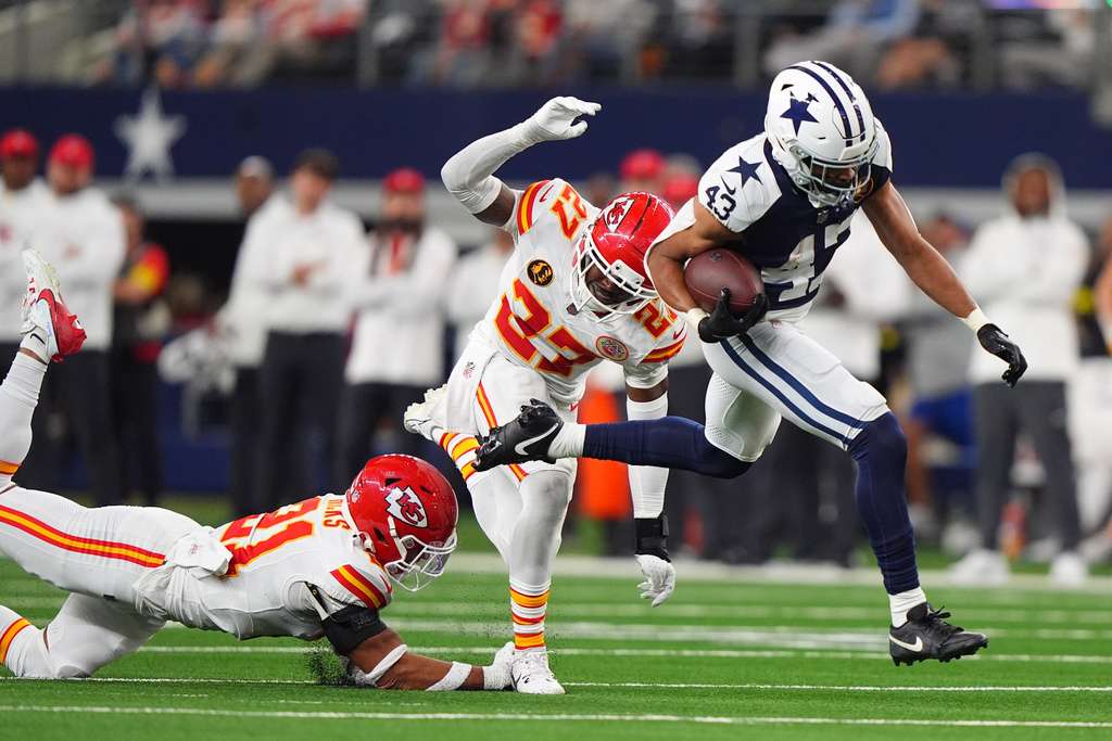 Dallas Cowboys running back Malik Davis, right, scores on a touchdown run past Kansas City Chiefs defensive back Chamarri Conner (27) and defensive back Jaden Hicks (21) during the first half of an NFL football game Thursday, Nov. 27, 2025, in Arlington, Texas. (AP Photo/LM Otero)