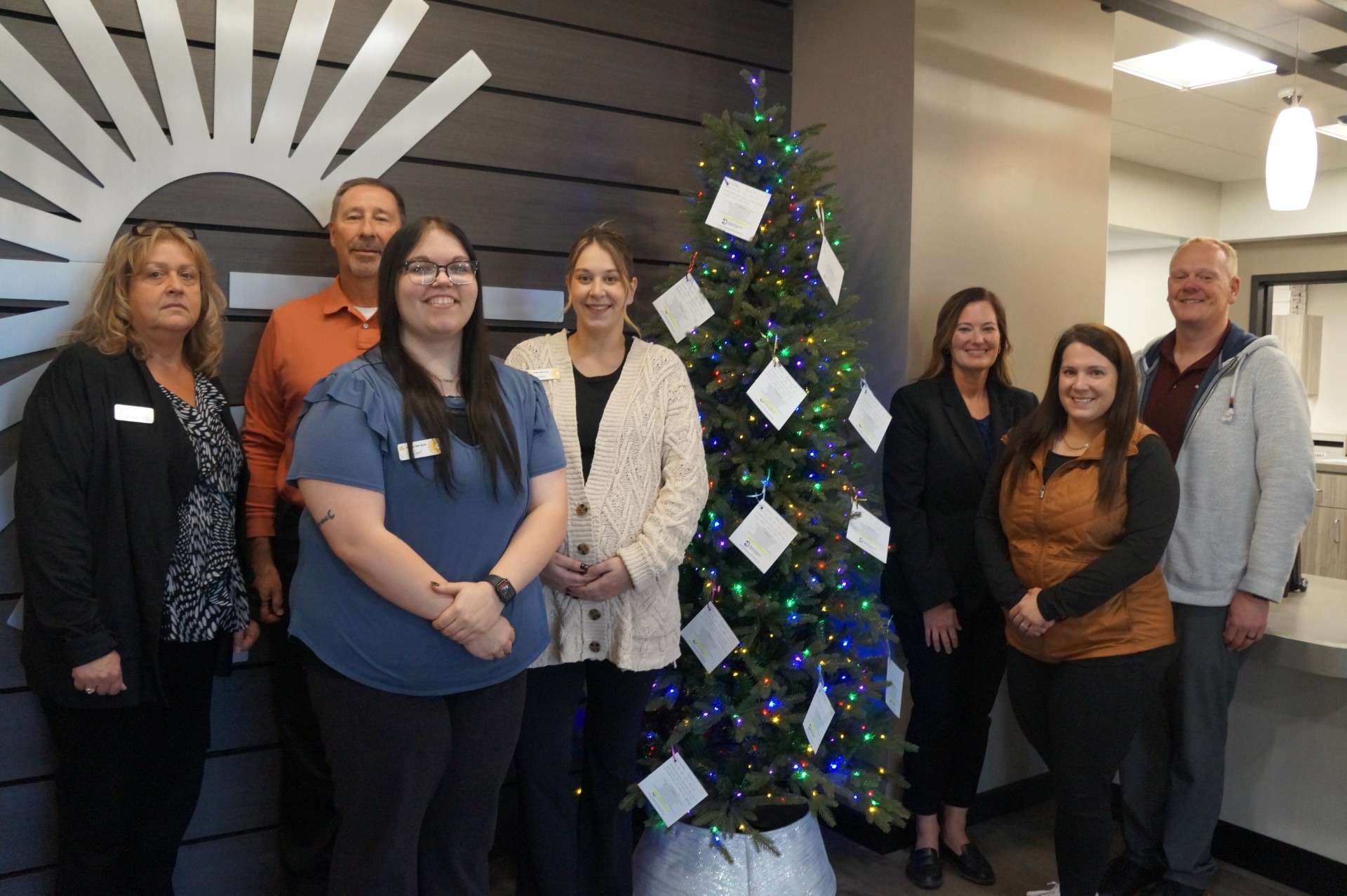 Golden Belt Bank employees gather at the Christmas for Kids Tree located in their lobby. From left are Donna Erickson, Randy Honas, Lexi Boeck, Azlyn Grasser, Jessica Kerr, Courtney Clark, and Jason Morford. Each “wish list” on the tree contains suggested gifts for foster children served by St. Francis Ministries in Ellis County and across northwest Kansas. Photo by Linn Ann Huntington